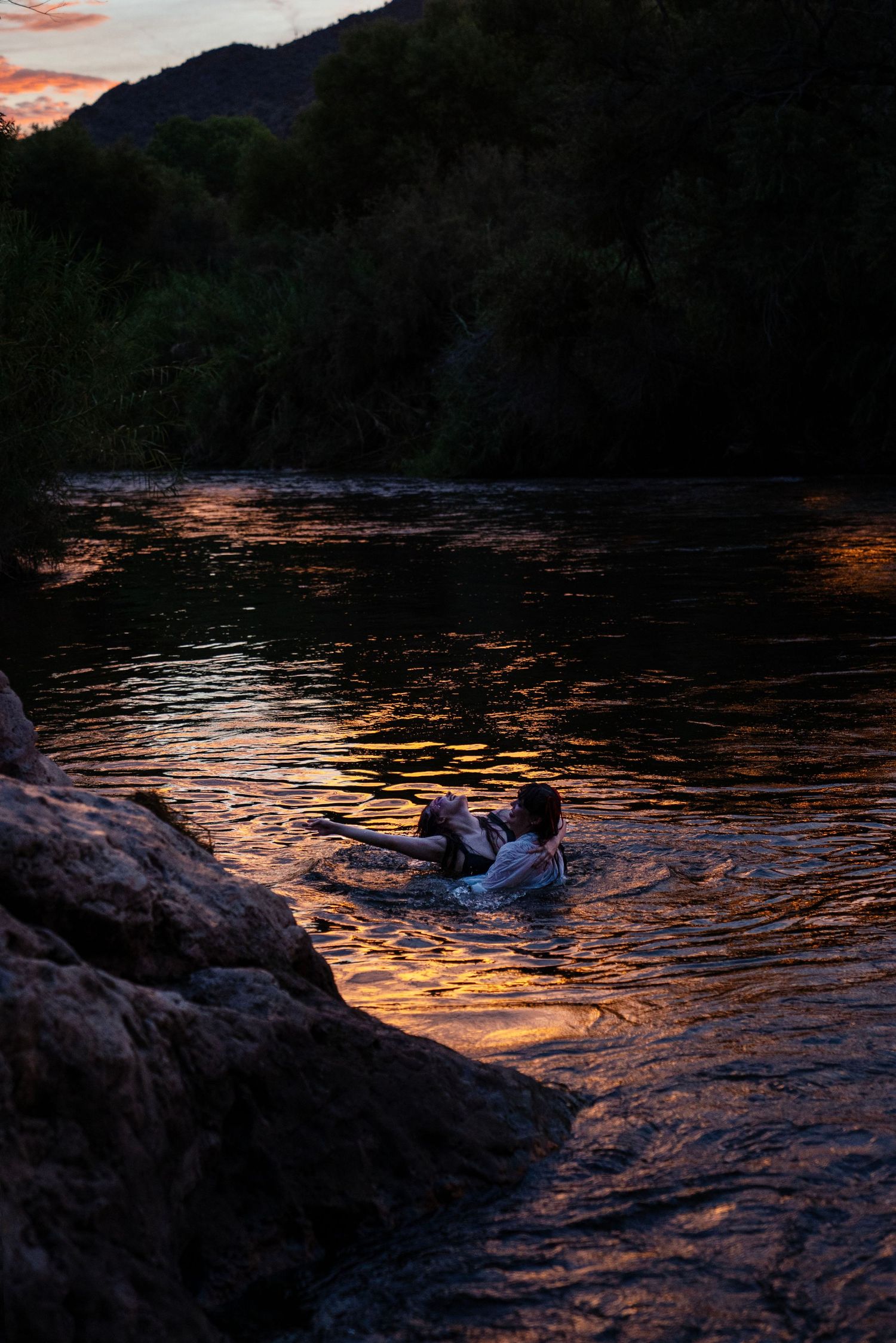 Person swimming in a glowing river at sunset with golden reflections on the water. Fantasy photoshoot. Arizona photograper