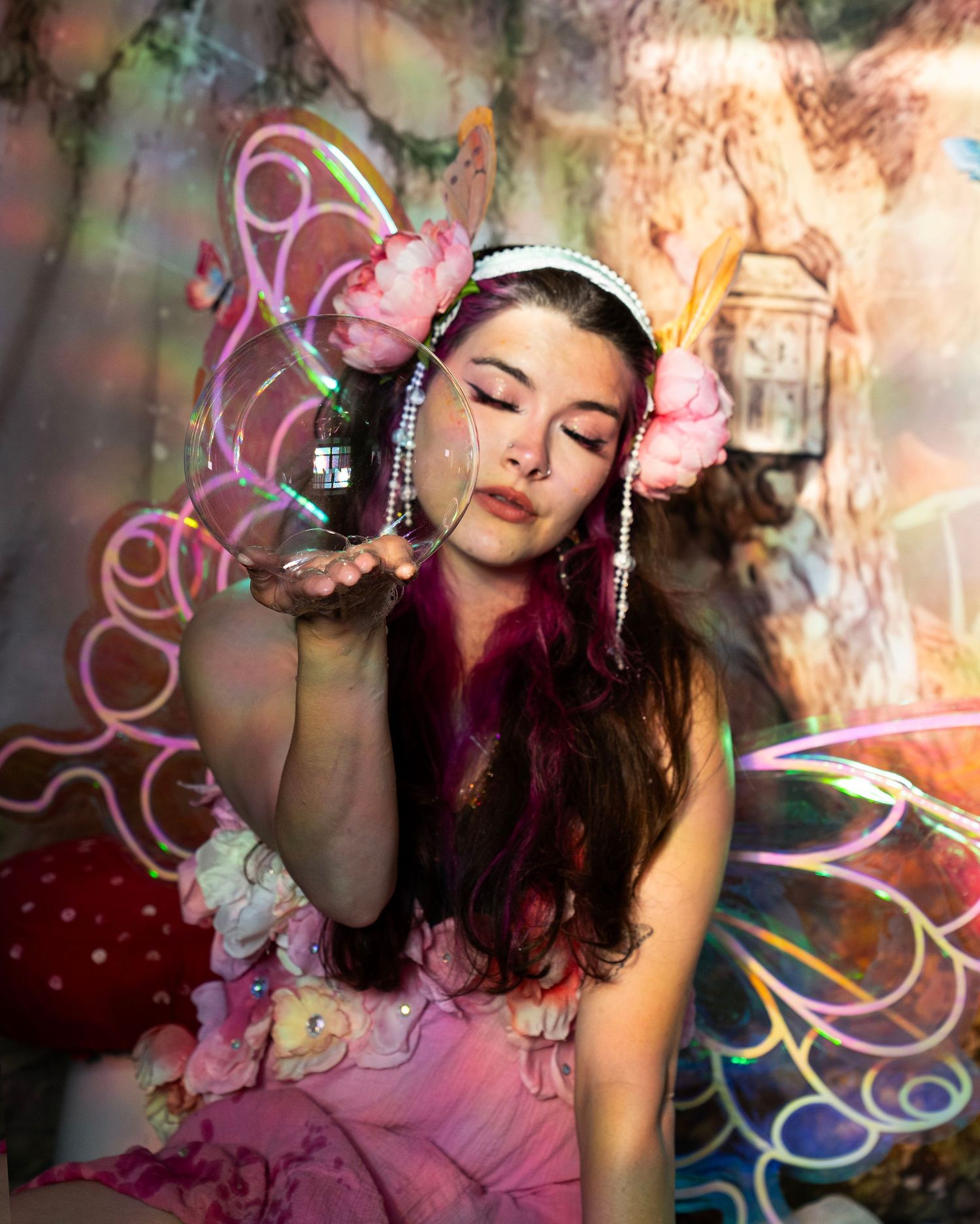 Woman dressed as a fairy blowing glitter from her hand in an enchanted forest setting. Fantasy Photoshoot