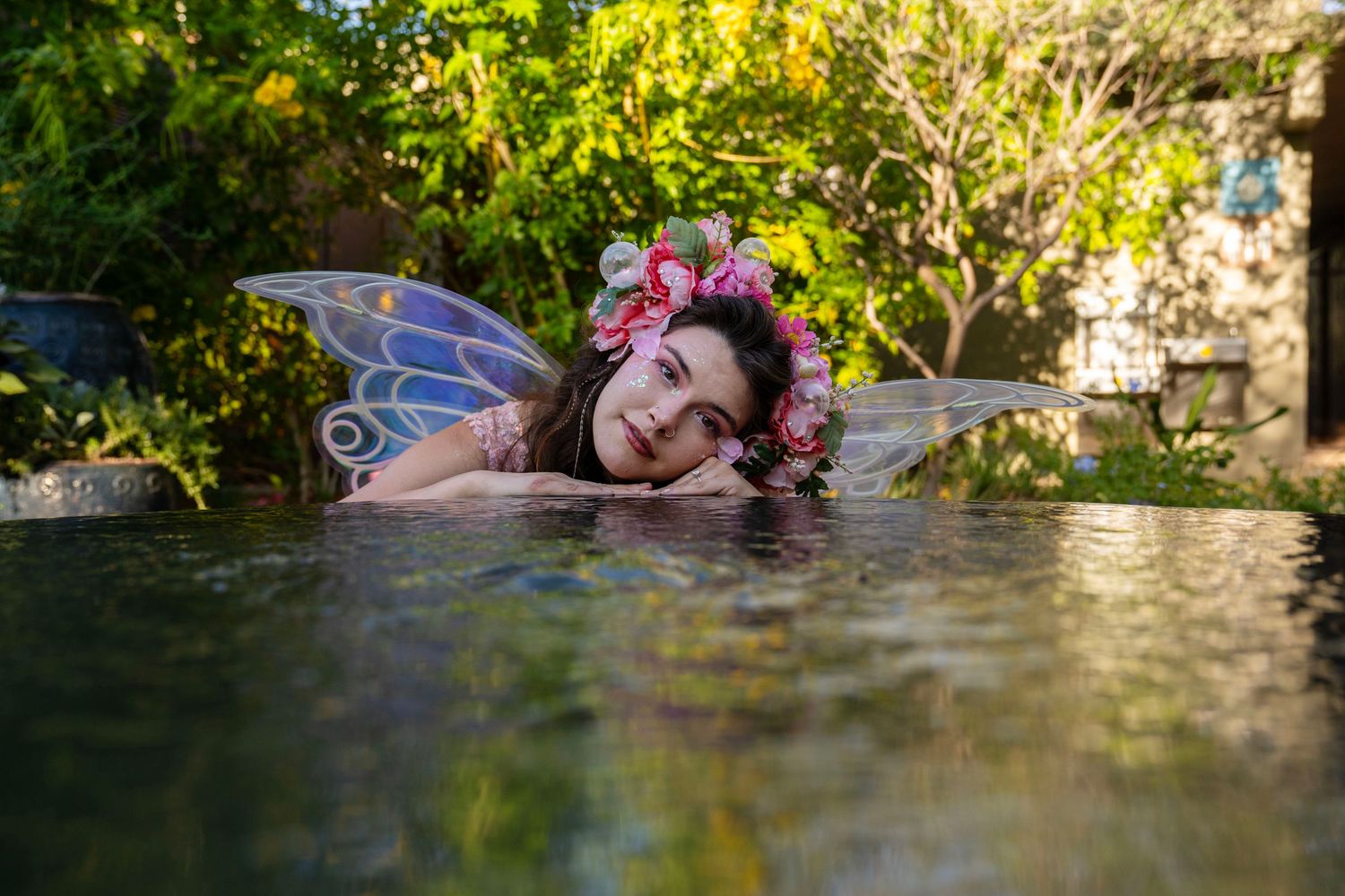 Fantasy photoshoot of a garden fairy. The pixie is lying upon a reflective pool.