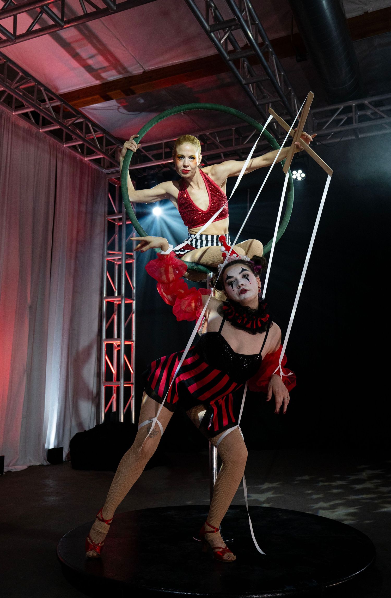 Two circus performers in red costumes pose with hula hoop and strings on stage. Circus Photoshoot