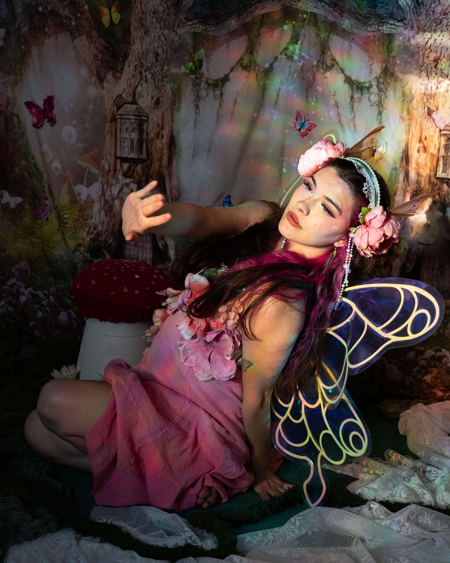 Woman in pink fairy dress with butterfly wings posing in a magical forest photo studio. Fantasy Photoshoot