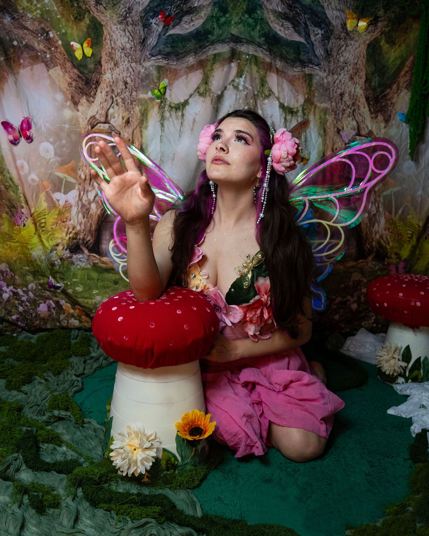 Fantasy fairy in pink dress holds crystal ball beside mushroom in enchanted forest set. Fantasy Photoshoot