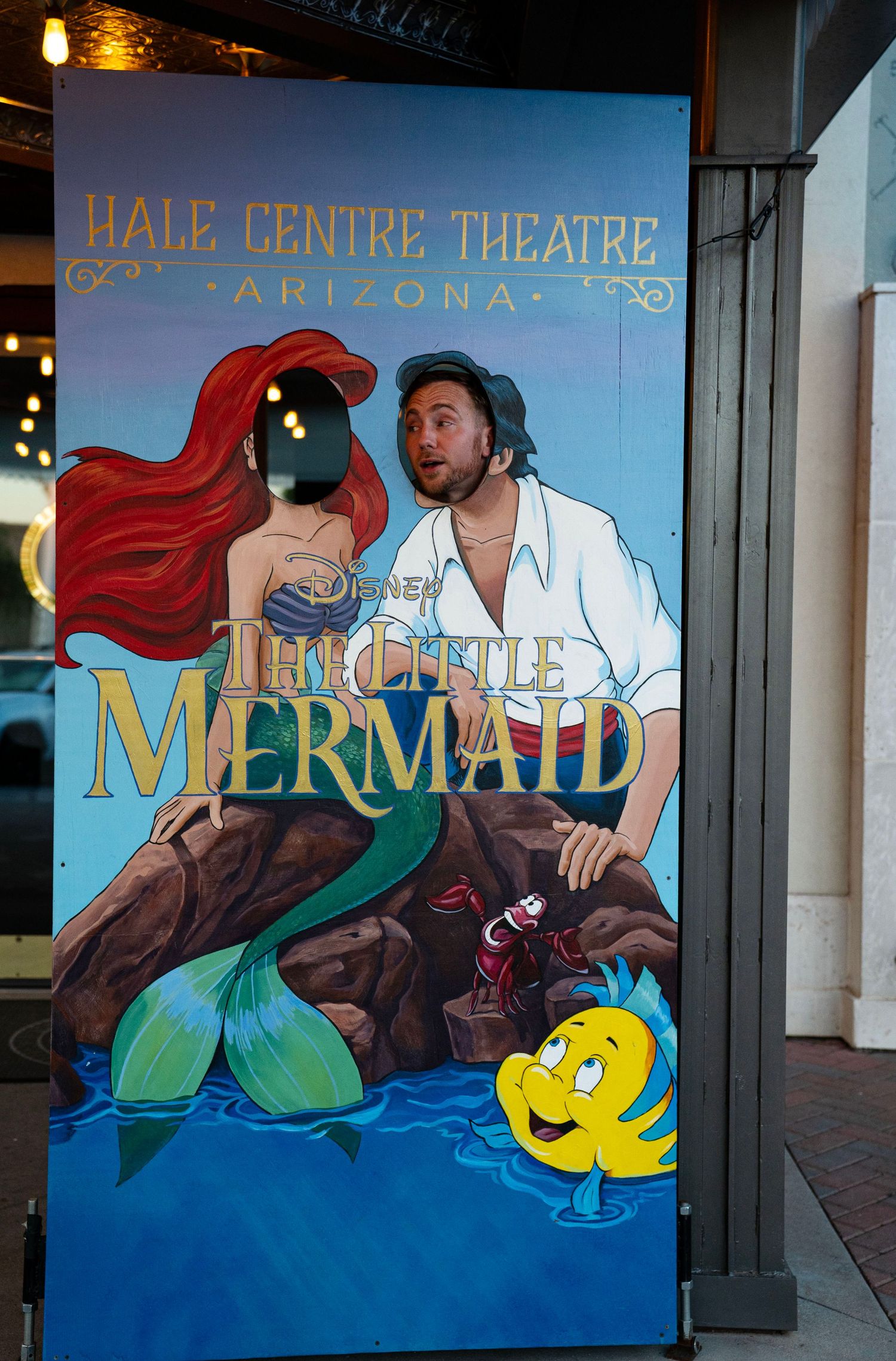 Man posing with Disney Little Mermaid promotional board at Hale Centre Theatre Arizona.