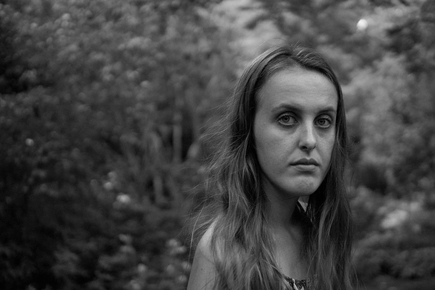 Black and white portrait of woman with long hair outdoors.