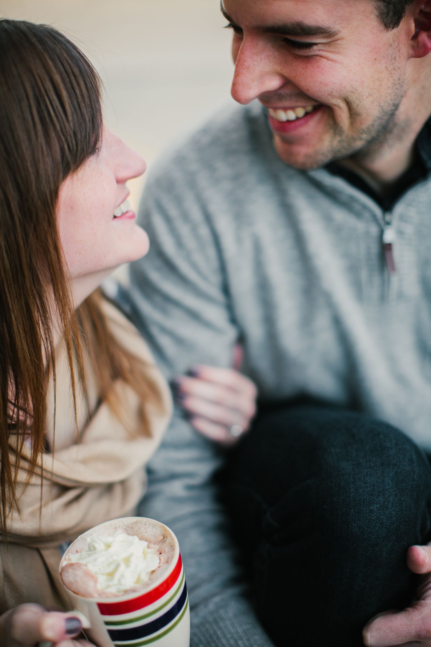 Smiling couple sharing an intimate moment while woman holds a whipped cream topped mug.