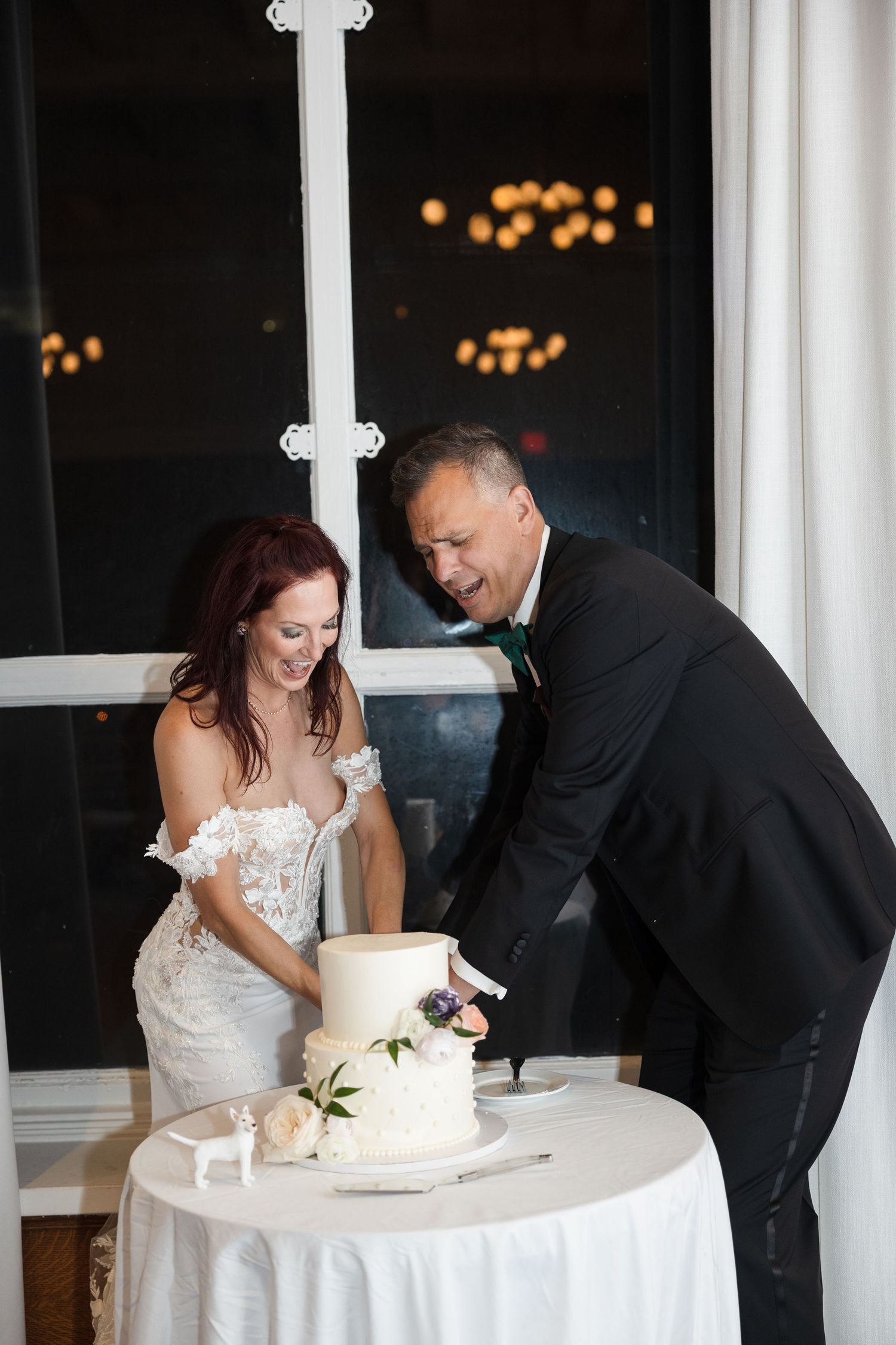 Bride and groom smiling while cutting a wedding cake at Le Méridien Tampa, Florida, captured by Grand Photo by Karyna Oliinyk