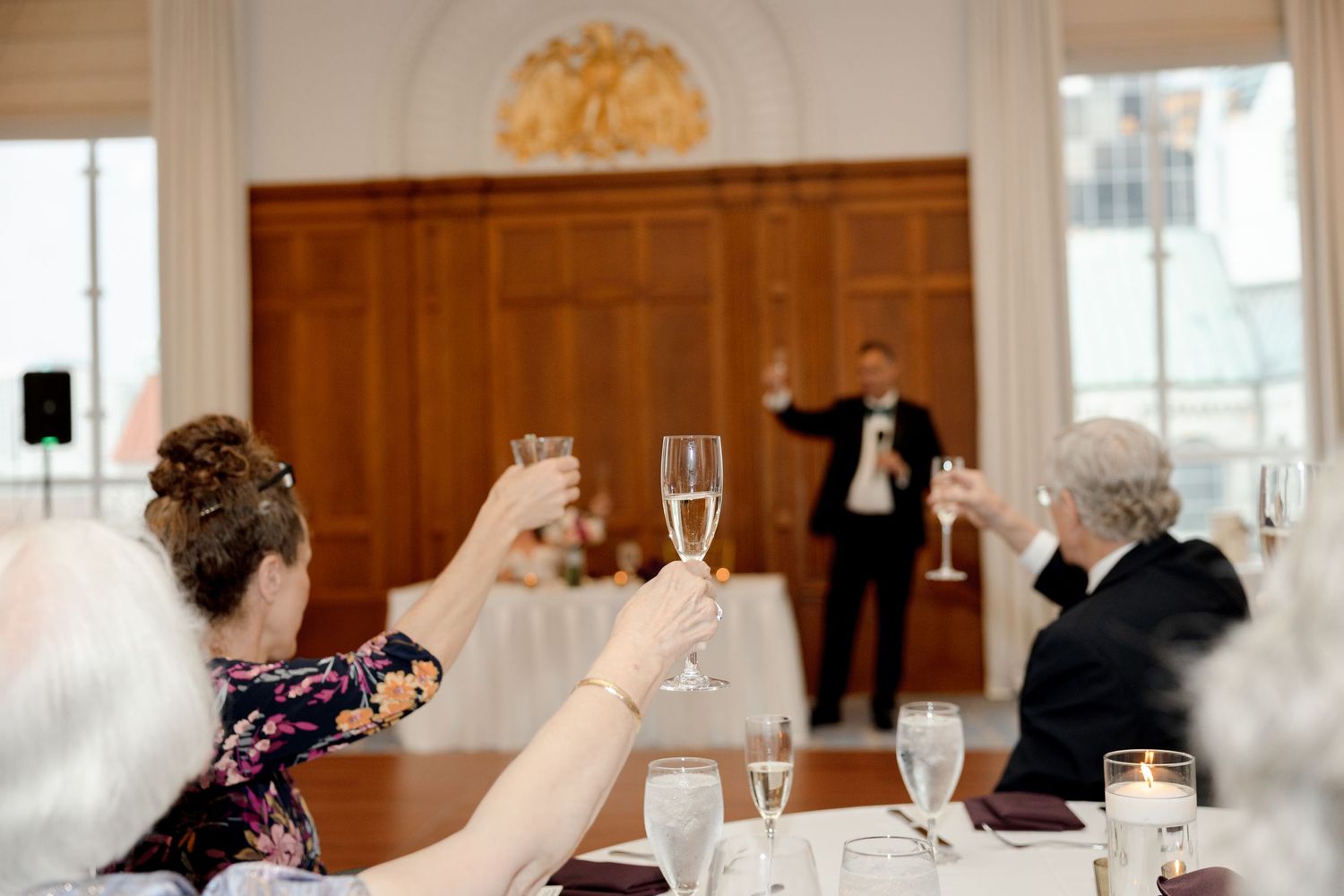 Wedding guests raising glasses in a toast during a reception at Le Méridien Tampa, Florida, captured by Grand Photo by Karyna Oliinyk