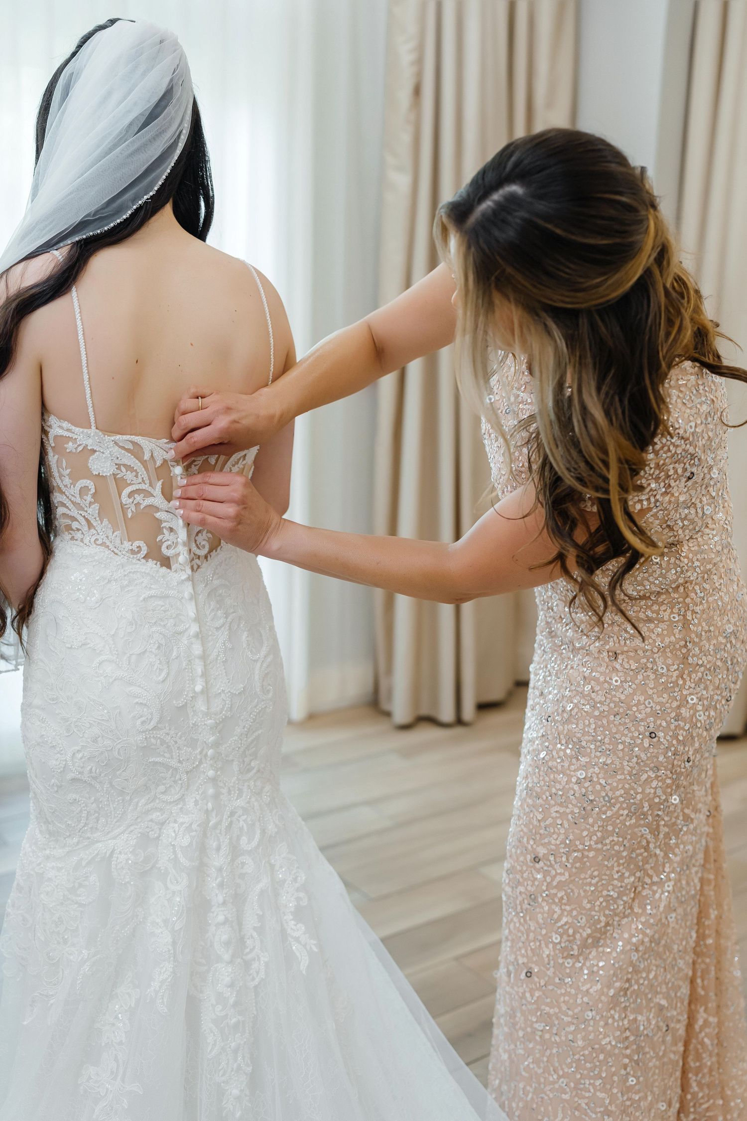 Bridesmaid zipping the bride’s dress at Harborside Chapel in Safety Harbor, Florida — wedding photographer Grand Photo, Karyna Oliinyk