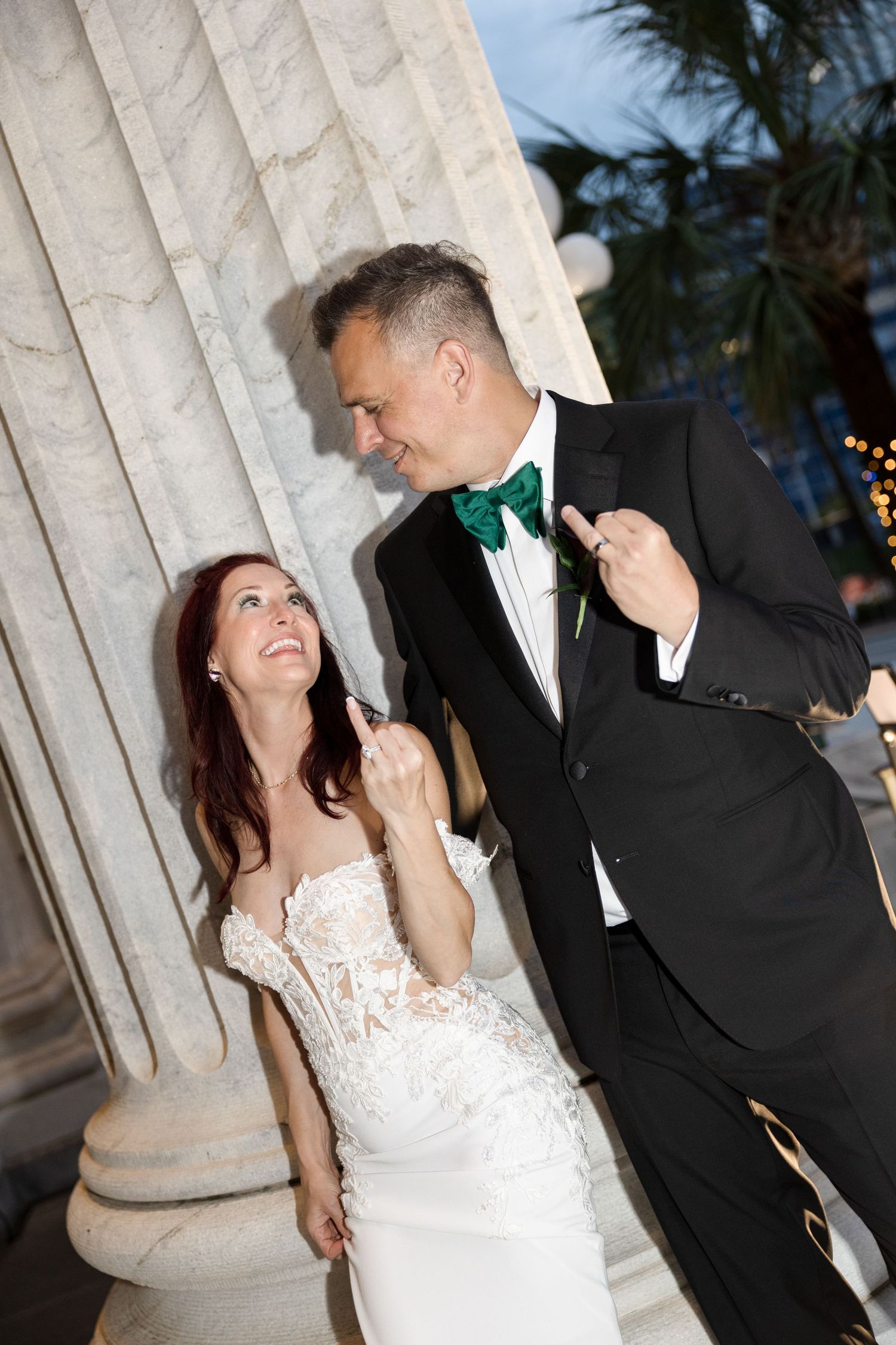 Bride and groom sharing a joyful moment by marble columns at night at Le Méridien Tampa, Florida, captured by Grand Photo by Karyna Oliinyk