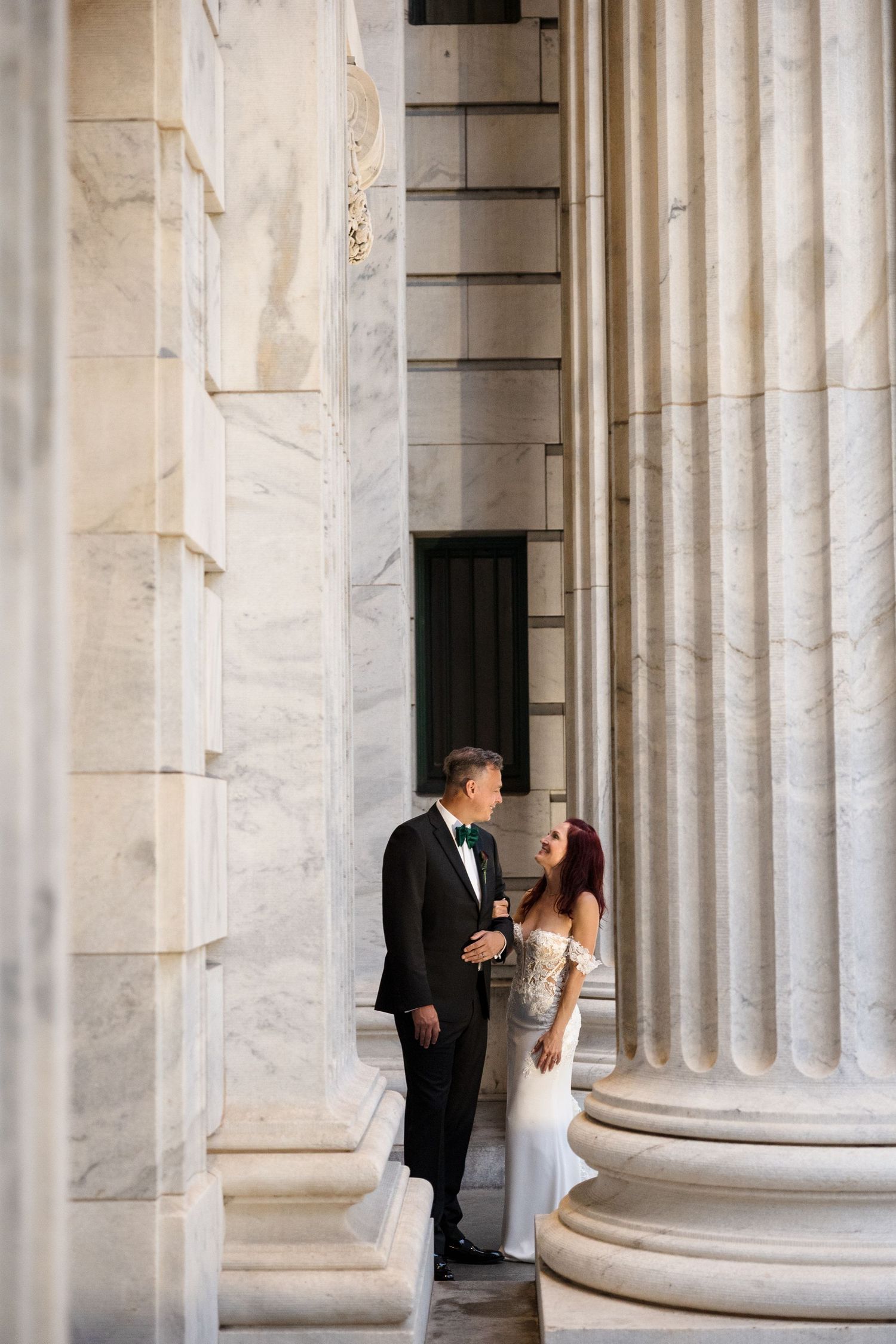 Bride and groom standing between grand marble columns at Le Méridien Tampa, Florida, captured by Grand Photo by Karyna Oliinyk