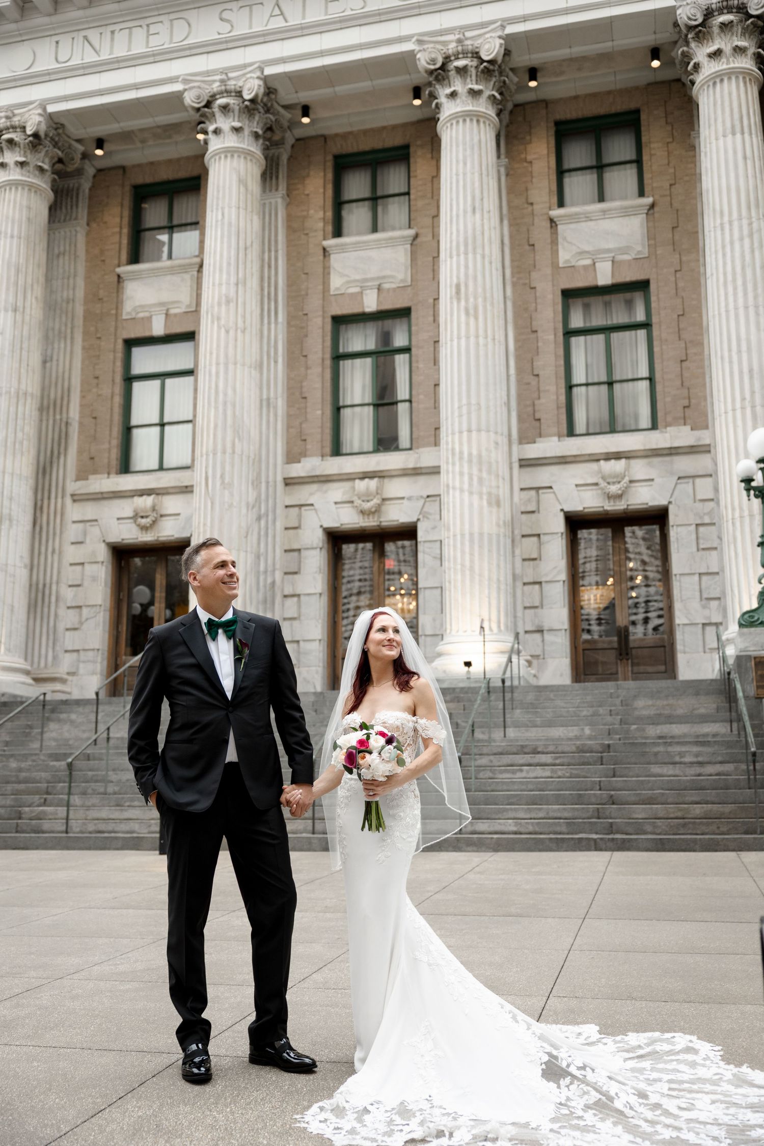 Bride and groom holding hands on steps of historic building at Le Méridien Tampa, Florida, captured by Grand Photo by Karyna Oliinyk