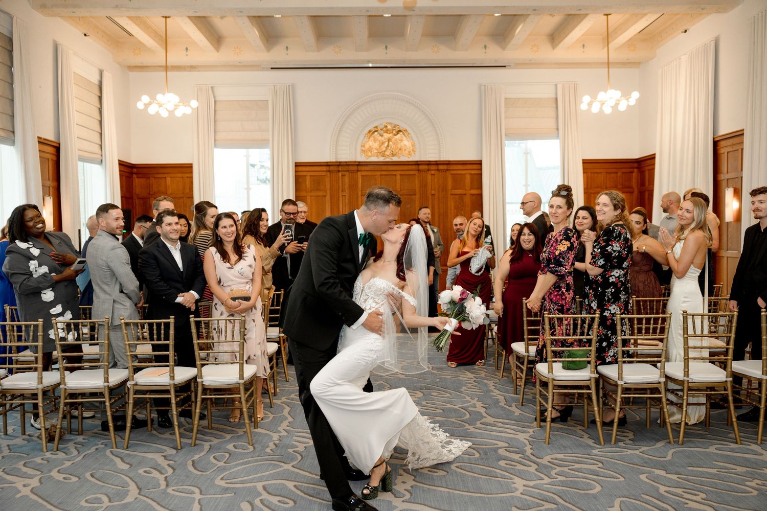 Groom dips bride at end of wedding ceremony aisle at Le Méridien Tampa, Florida, captured by Grand Photo by Karyna Oliinyk