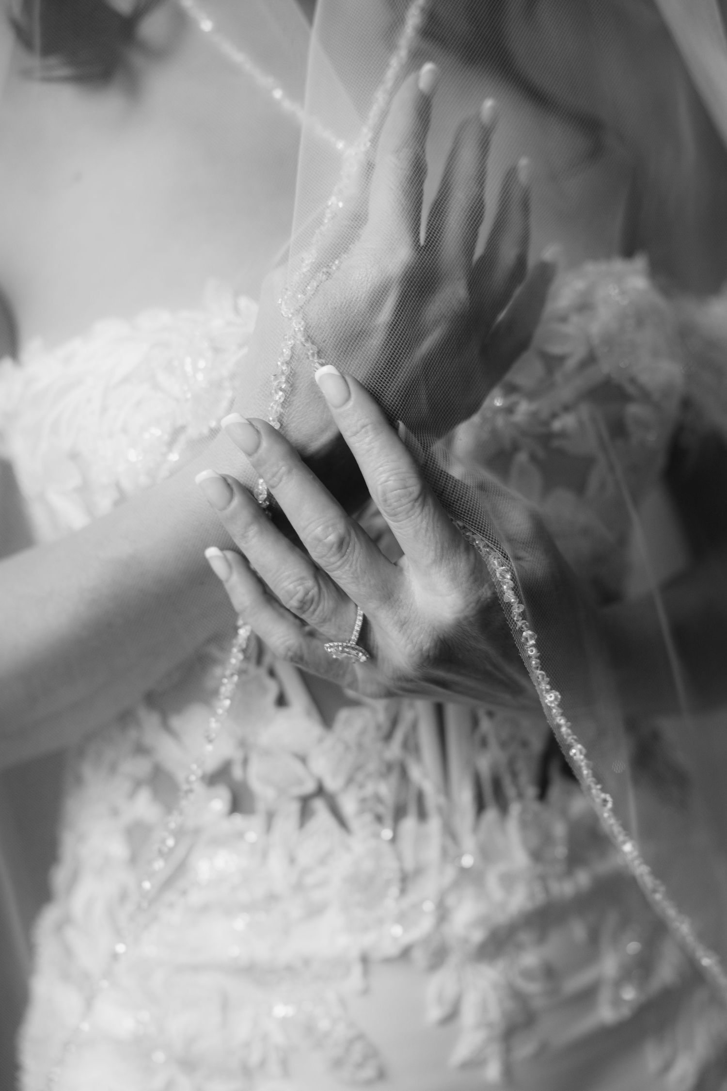 Black and white close-up of bride's hands holding wedding veil at Le Méridien Tampa, Florida, captured by Grand Photo by Karyna Oliinyk