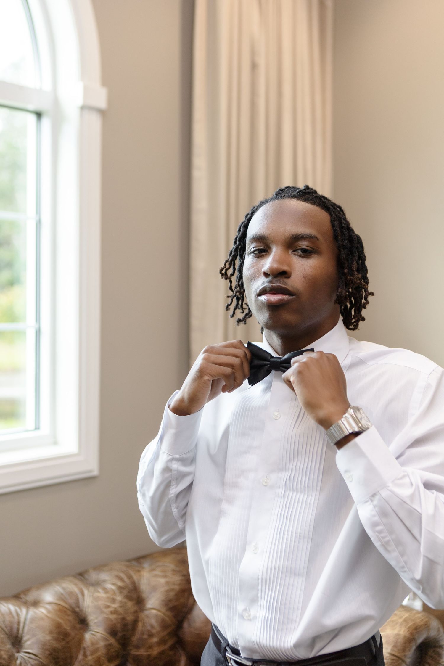 Black groom putting on a bow tie at Harborside Chapel in Safety Harbor, Florida — wedding photographer Grand Photo, Karyna Oliinyk