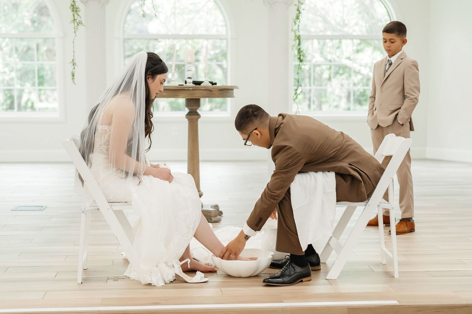 Groom washing the bride’s foot during the wedding ceremony at Harborside Chapel in Safety Harbor — wedding photographer Grand Photo