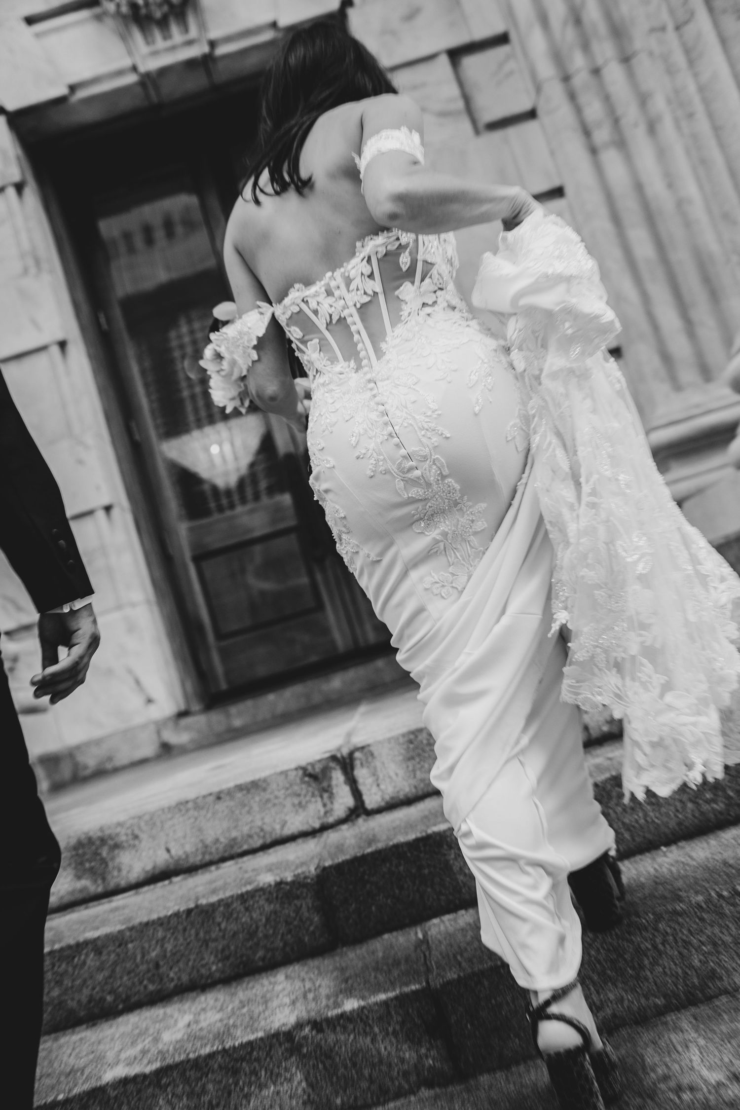 Black and white photo of a bride in a lace wedding gown walking at Le Méridien Tampa, Florida, captured by Grand Photo by Karyna Oliinyk