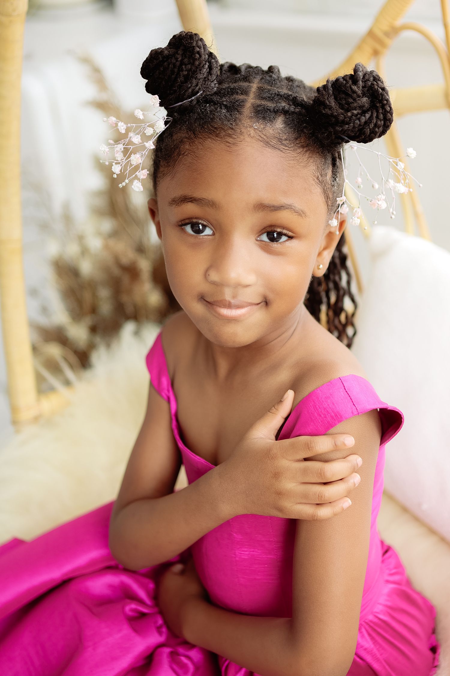 Adorable young girl in hot pink off-shoulder dress with braided bun updo and floral hair pins.