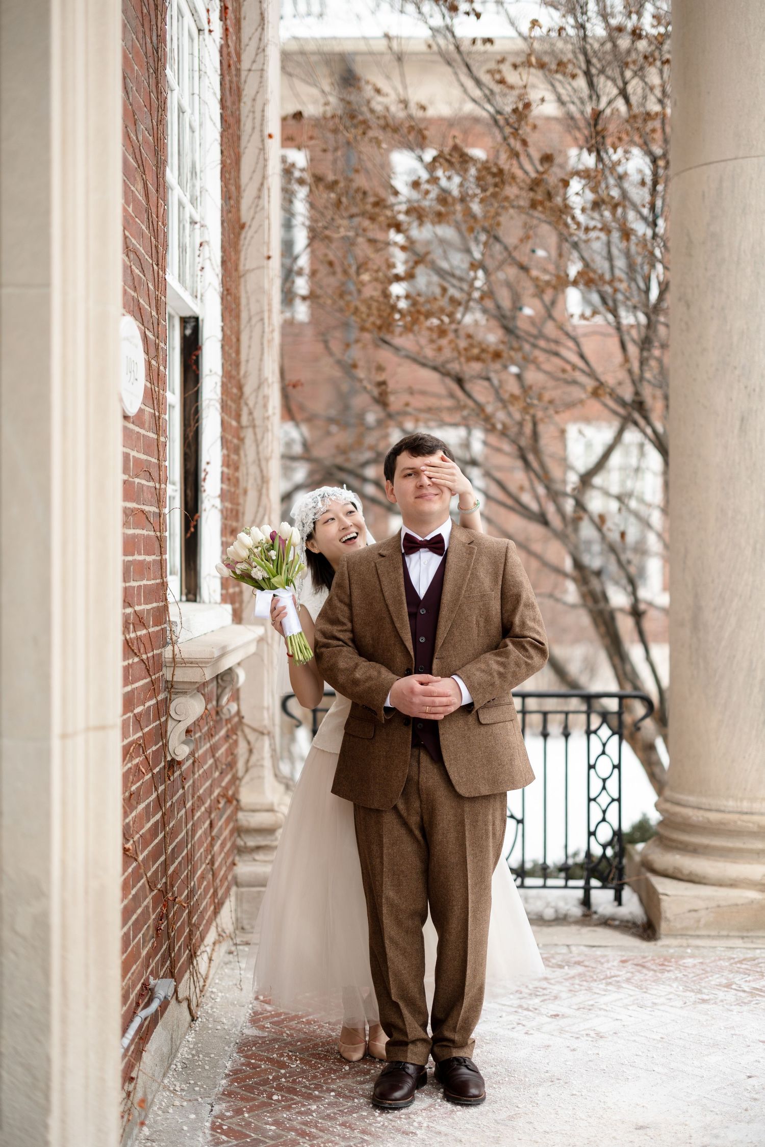 Playful bride covering groom’s eyes outside Newton City Hall in Newton, Massachusetts, captured by Grand Photo by Karyna Oliinyk