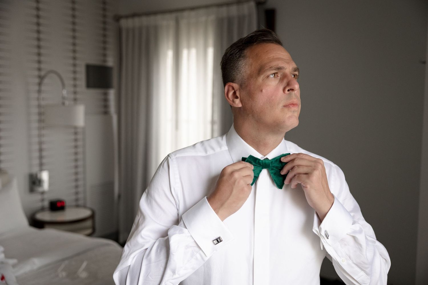 A groom adjusting a bow tie before the ceremony at Le Méridien Tampa, Florida, captured by Grand Photo by Karyna Oliinyk