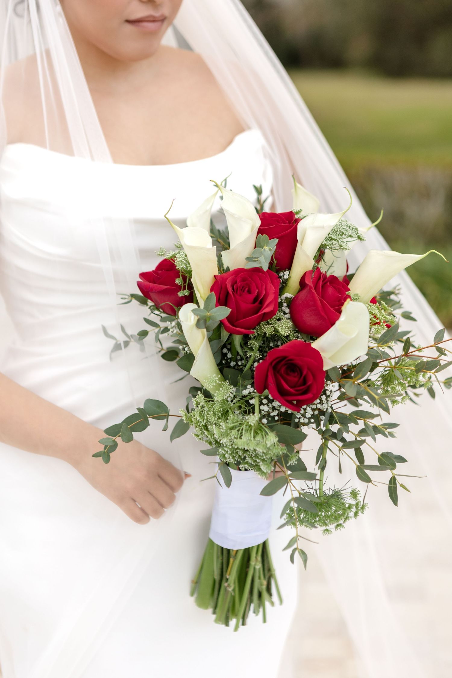 Bride holding a bouquet of red roses and white calla lilies at Harborside Chapel in Safety Harbor — wedding photographer Grand Photo