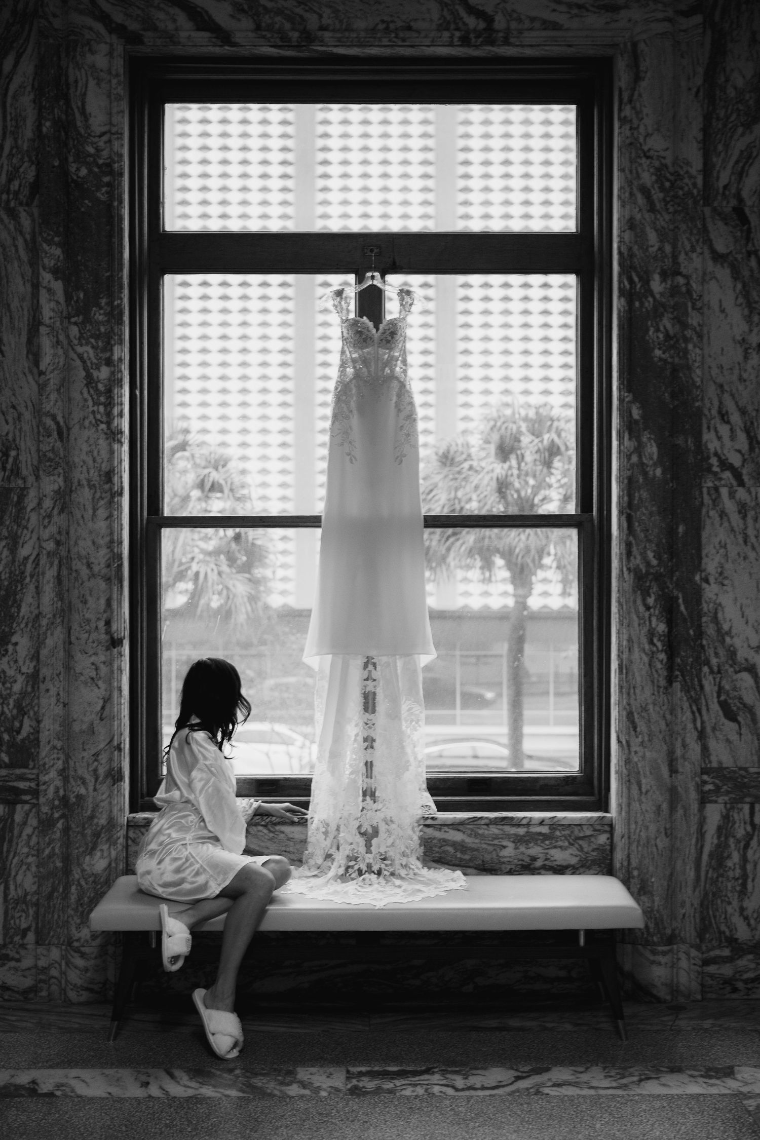 Bride looking at the dress hanging on the window at Le Méridien Tampa, Florida, captured by Grand Photo by Karyna Oliinyk
