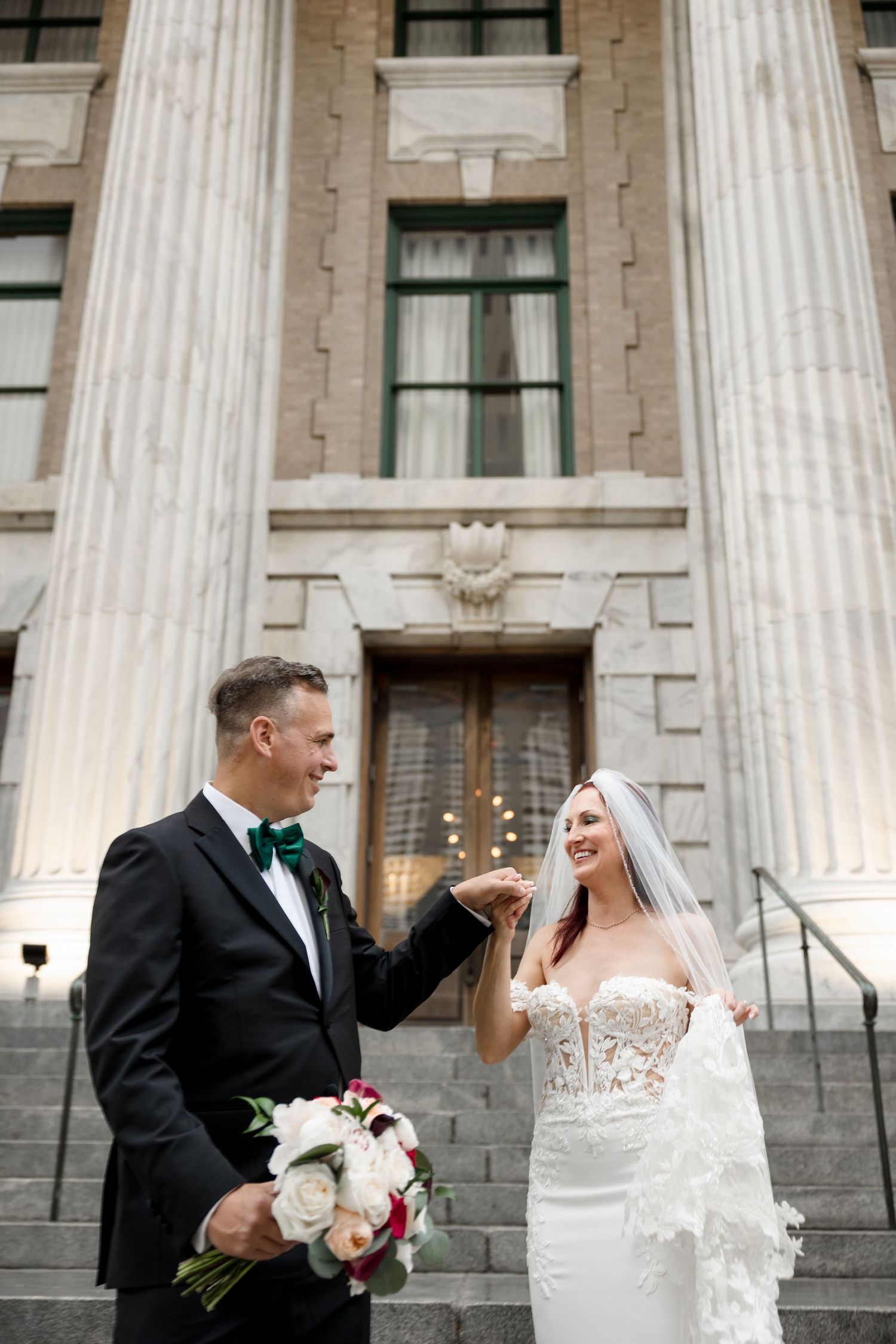 Bride and groom share a joyful moment on grand staircase at Le Méridien Tampa, Florida, captured by Grand Photo by Karyna Oliinyk