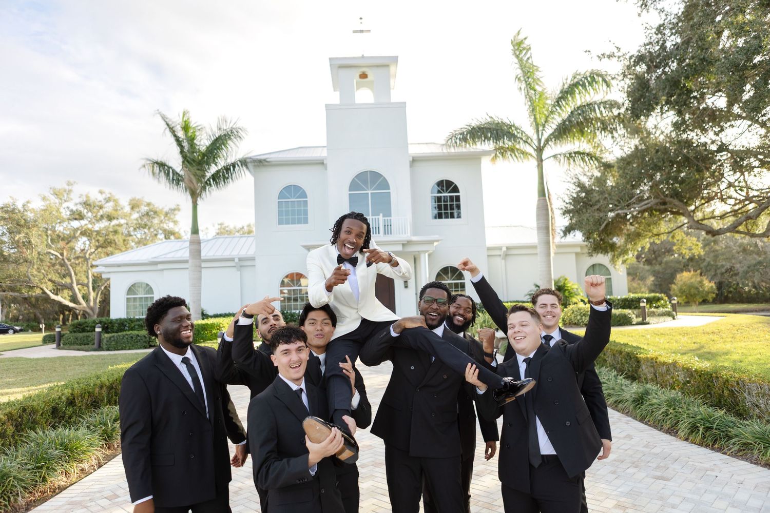 Groomsmen celebrate by lifting groom outside Harborside Chapel in Safety Harbor, Florida, captured by Grand Photo by Karyna Oliinyk