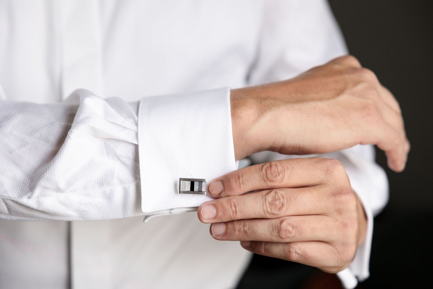 Groom fastening a silver and black rectangular cufflink at Le Méridien Tampa, Florida, captured by Grand Photo by Karyna Oliinyk
