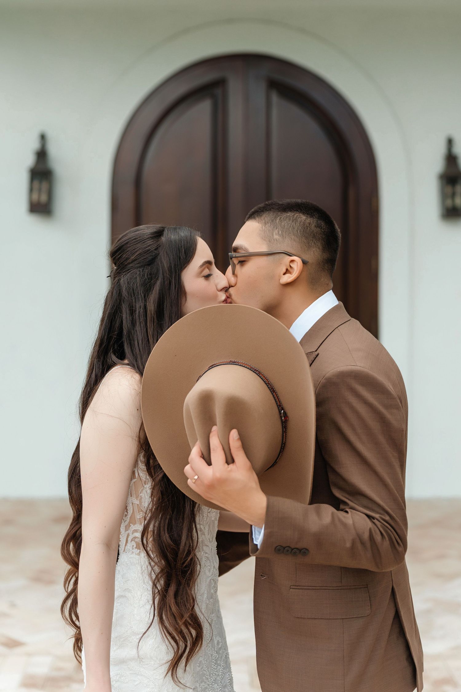 Bride and groom kissing behind a cowboy hat at Harborside Chapel in Safety Harbor — wedding photographer Grand Photo, Karyna Oliinyk