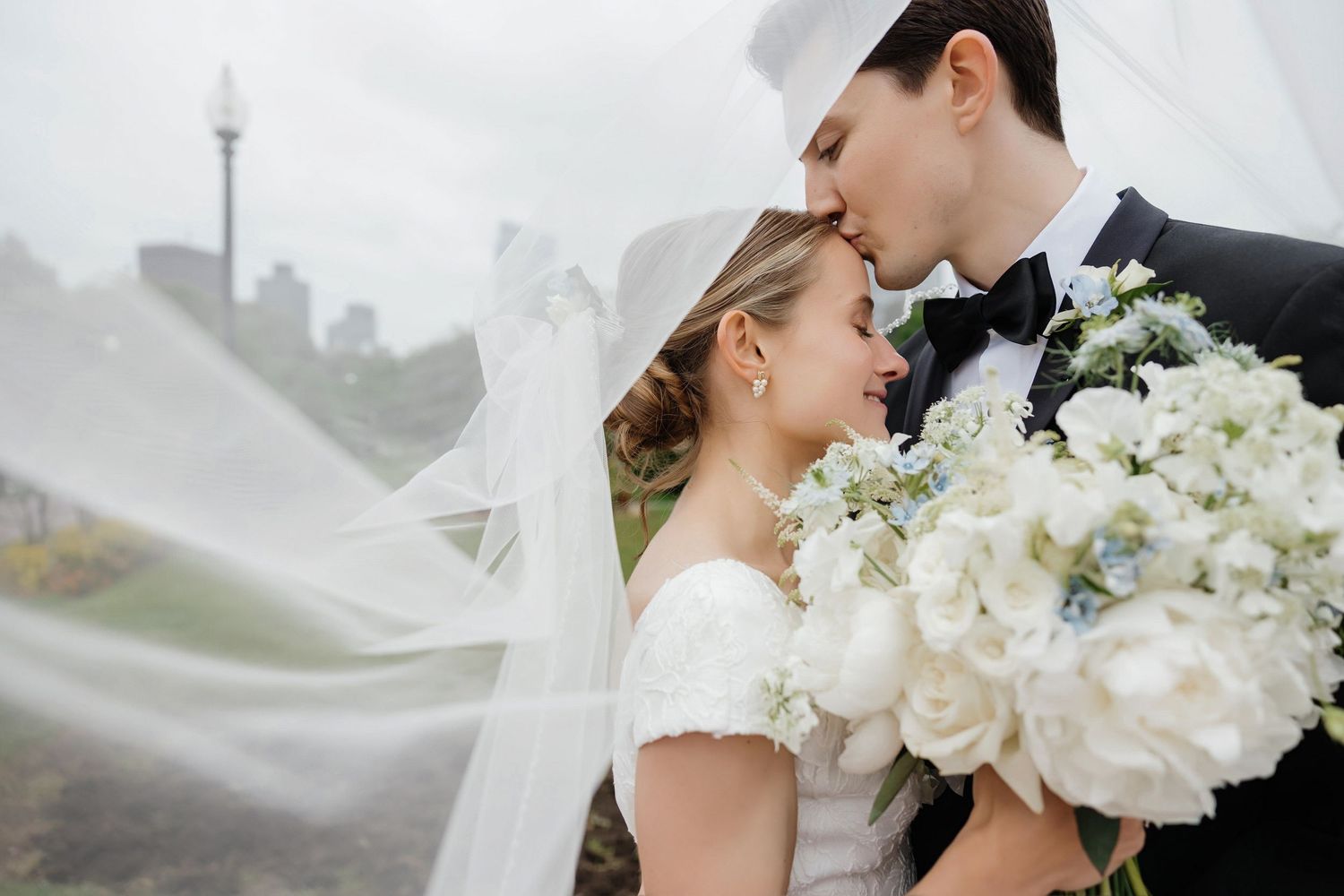 Romantic bride and groom kissing under flowing veil with white floral bouquet — St. Petersburg FL wedding photographer Grand Photo