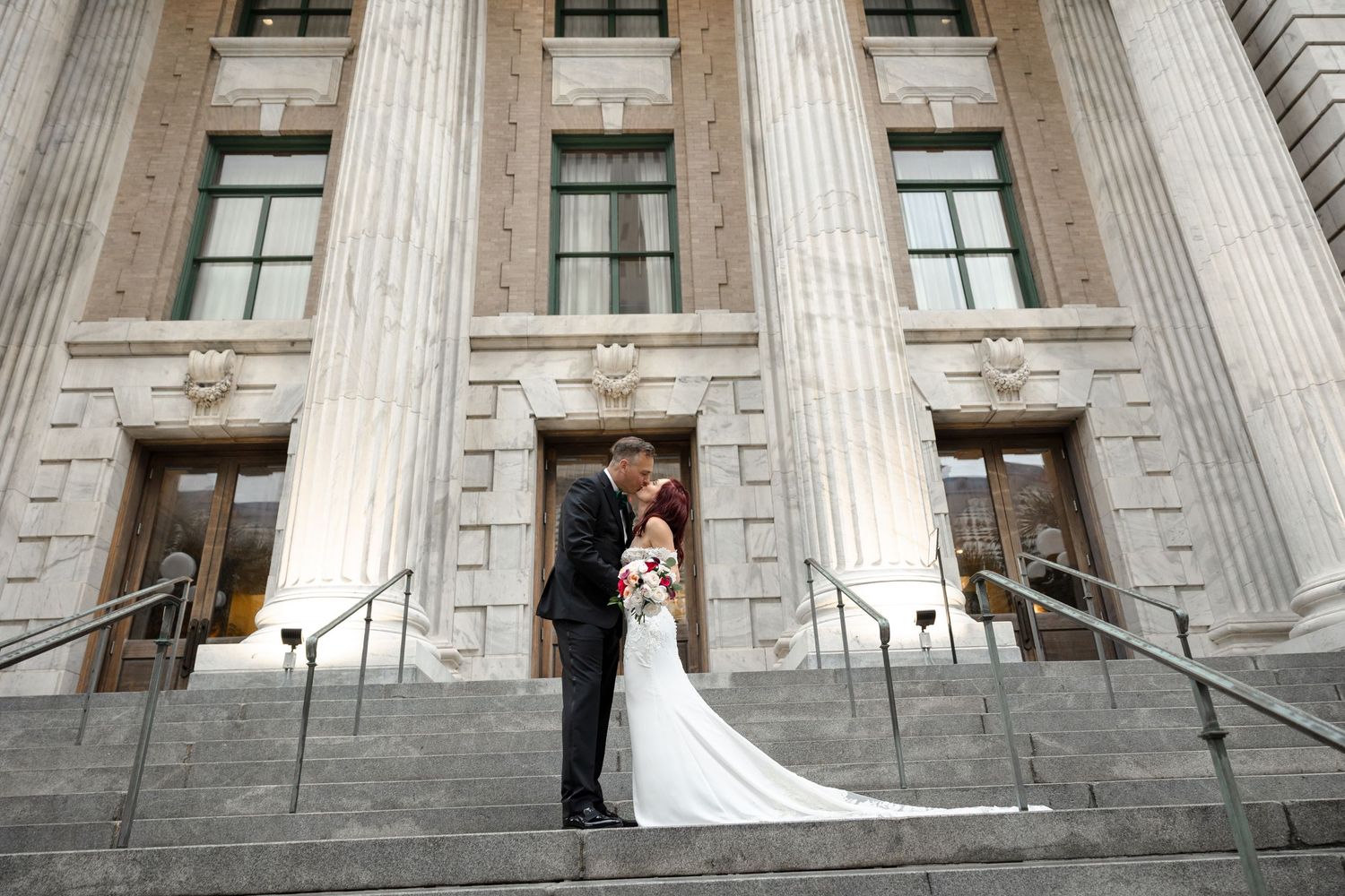 Bride and groom share a romantic kiss on grand stone steps at Le Méridien Tampa, Florida, captured by Grand Photo by Karyna Oliinyk