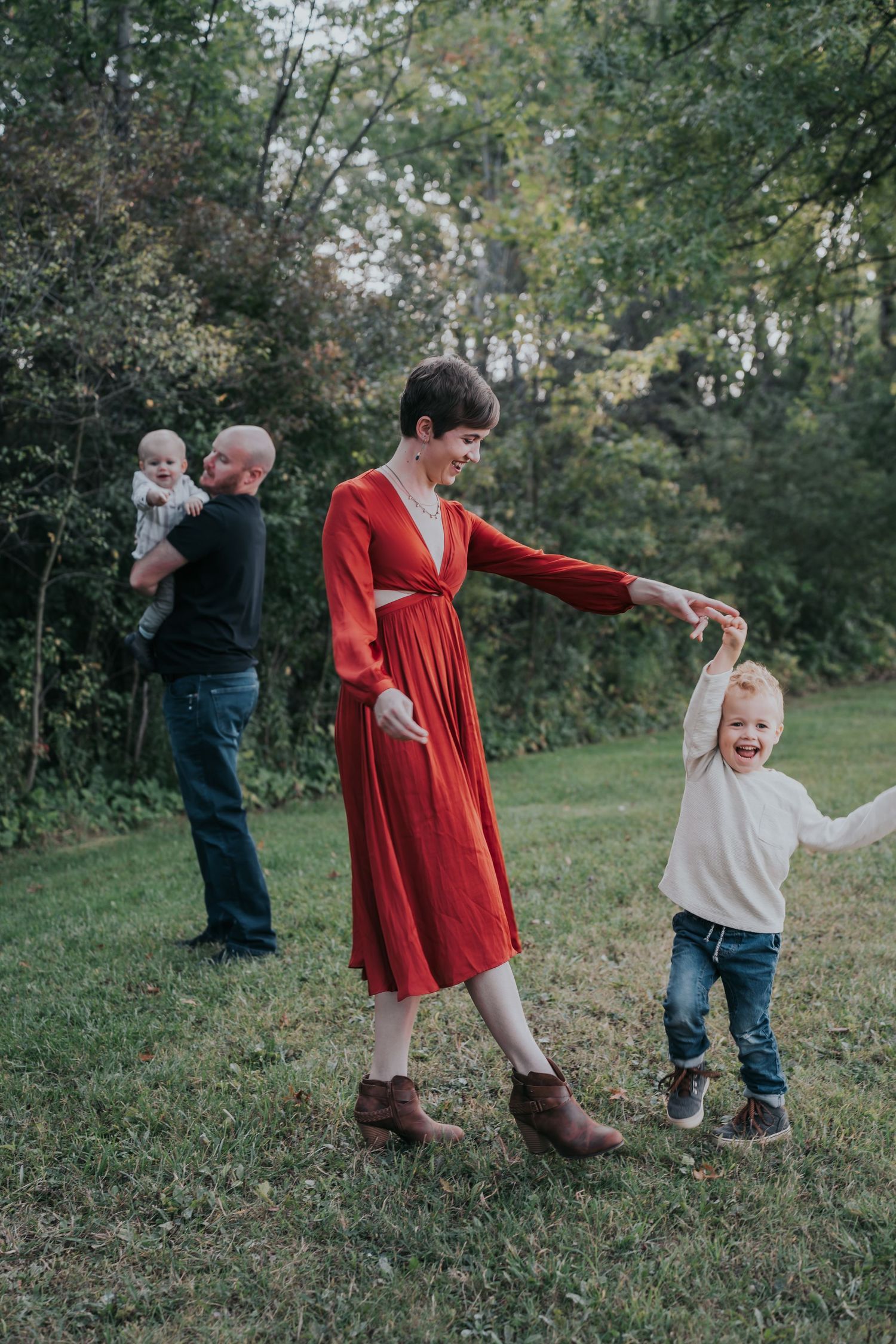 A series of four outdoor photos showing adults and children holding hands and playing in a grass field on an autumn day.