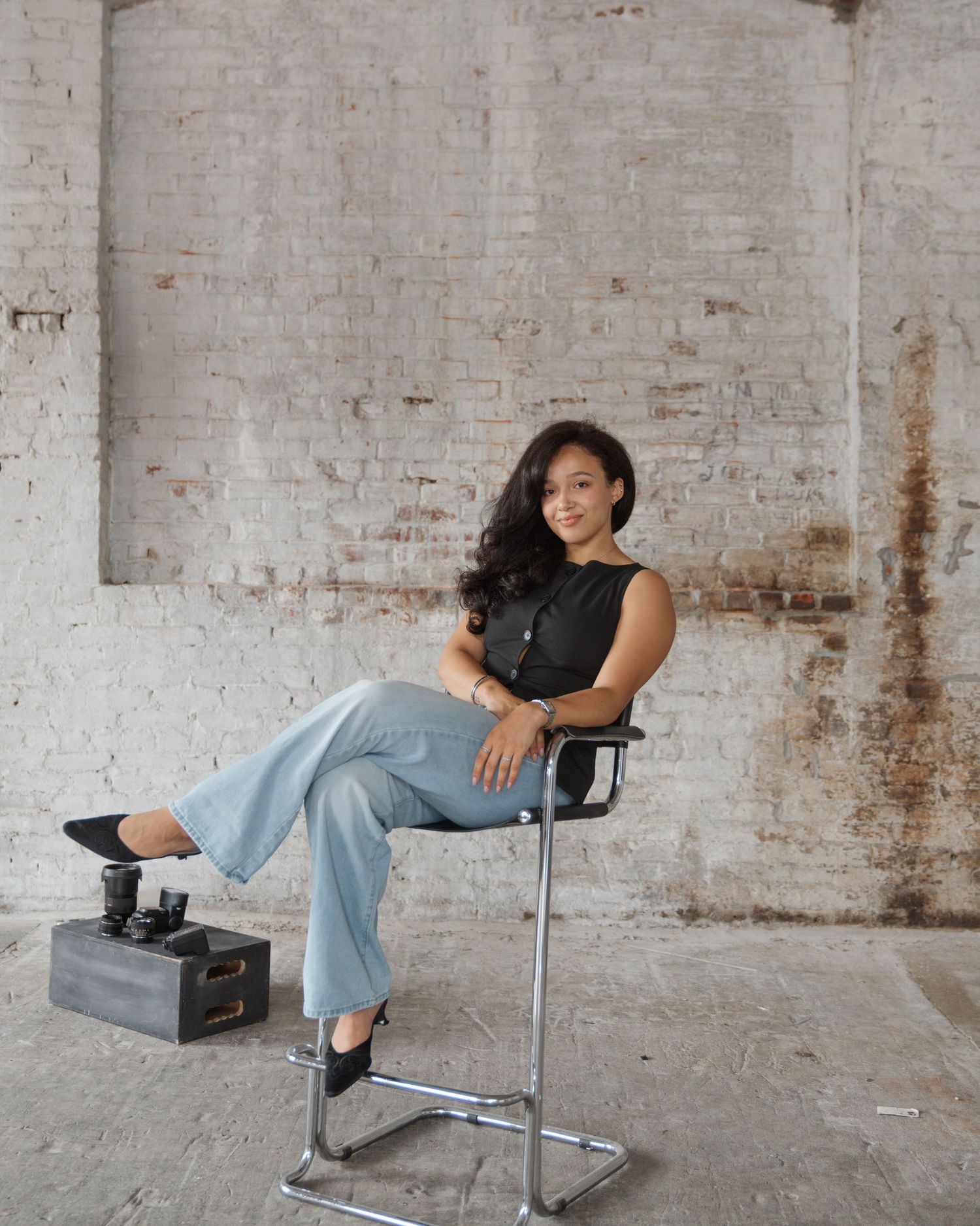 Studio portrait in industrial space with exposed brick walls and modern chair.