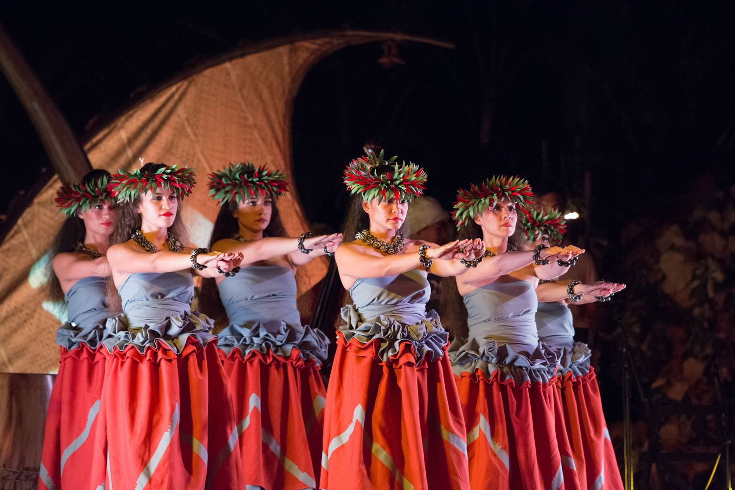 Dancers in matching red and white costumes perform a synchronized dance routine on stage during a performance.