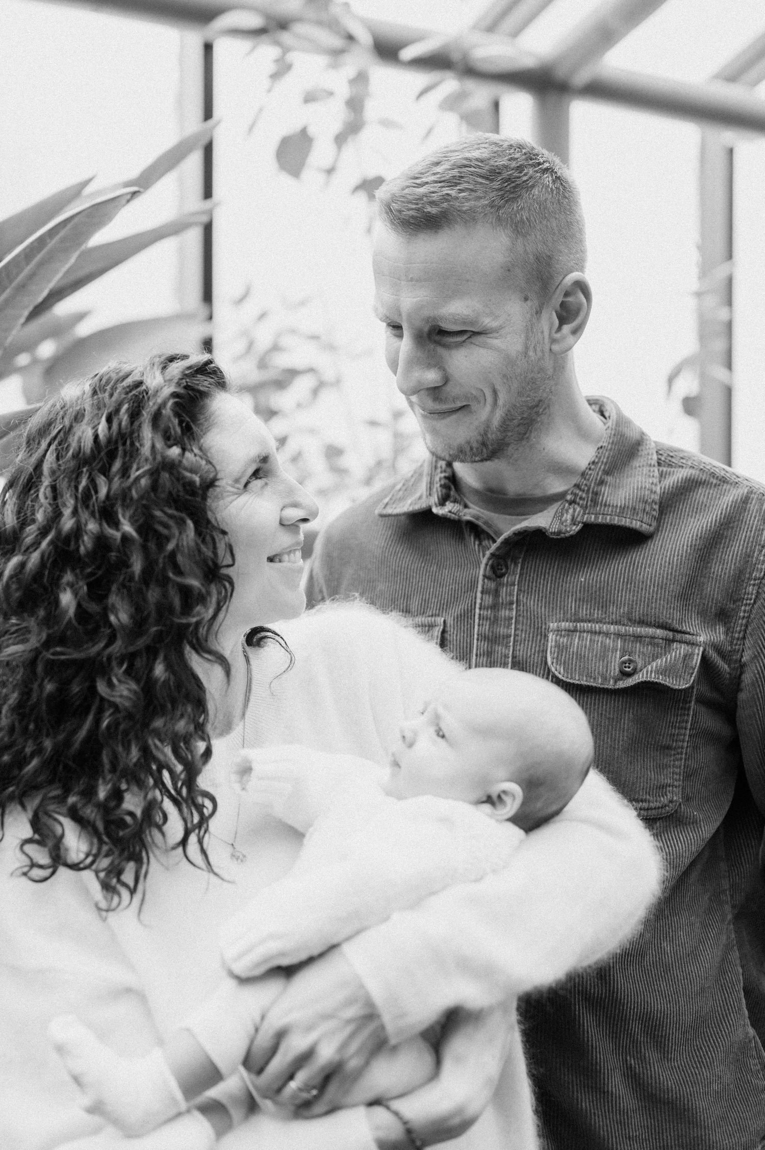 Black and white photo of parents smiling at their newborn baby. Minneapolis newborn photoshoot.