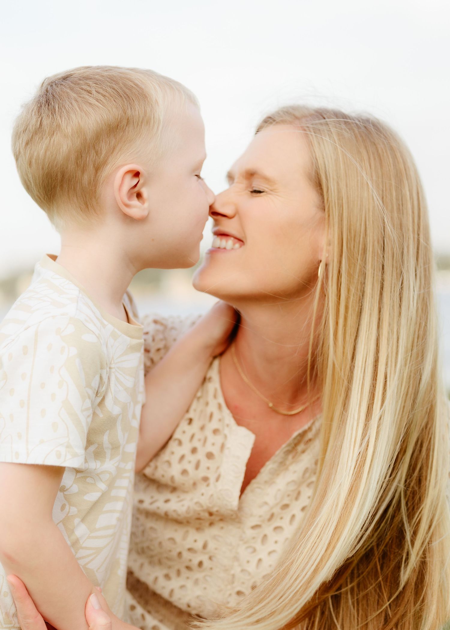 Blonde mother smiles as her young toddler son leans in for a sweet nose-to-nose moment. Twin cities family photographer.