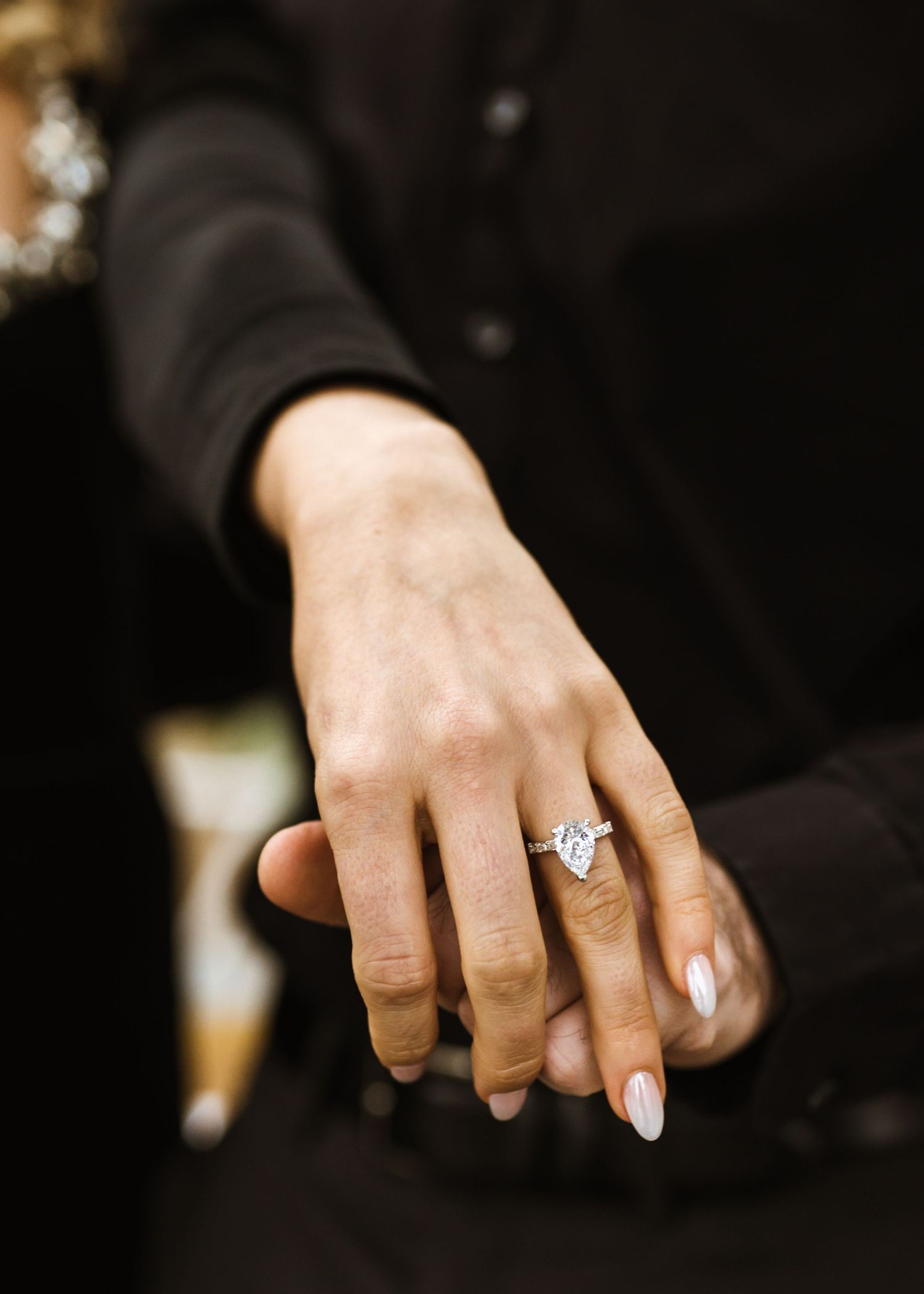 Close-up of a hand displaying a marquise diamond engagement ring on the ring finger.