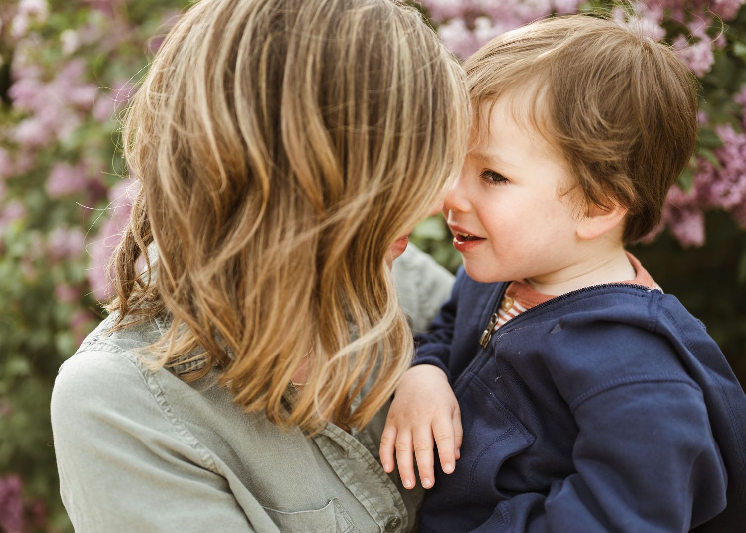 Tender close-up of a mother and her young child sharing a sweet face-to-face moment outdoors.