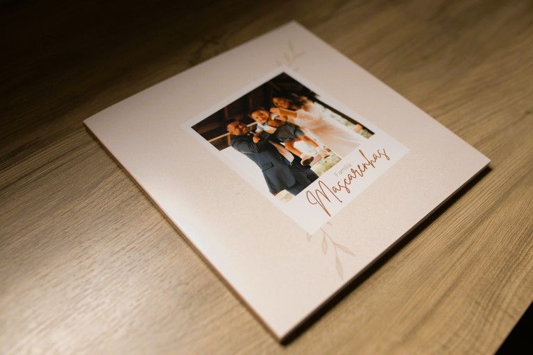 Pink wedding photo album on wooden table with couple photo and elegant script text on cover.