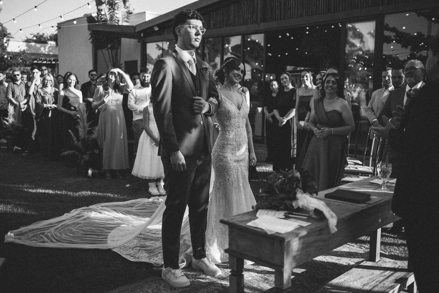 Black and white photo of a bride and groom standing at the altar during an outdoor wedding ceremony.