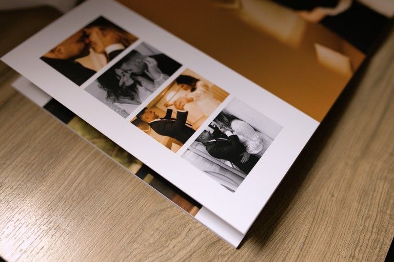 A photo book open on a wooden table displaying a collage of black and white and color wedding photographs.