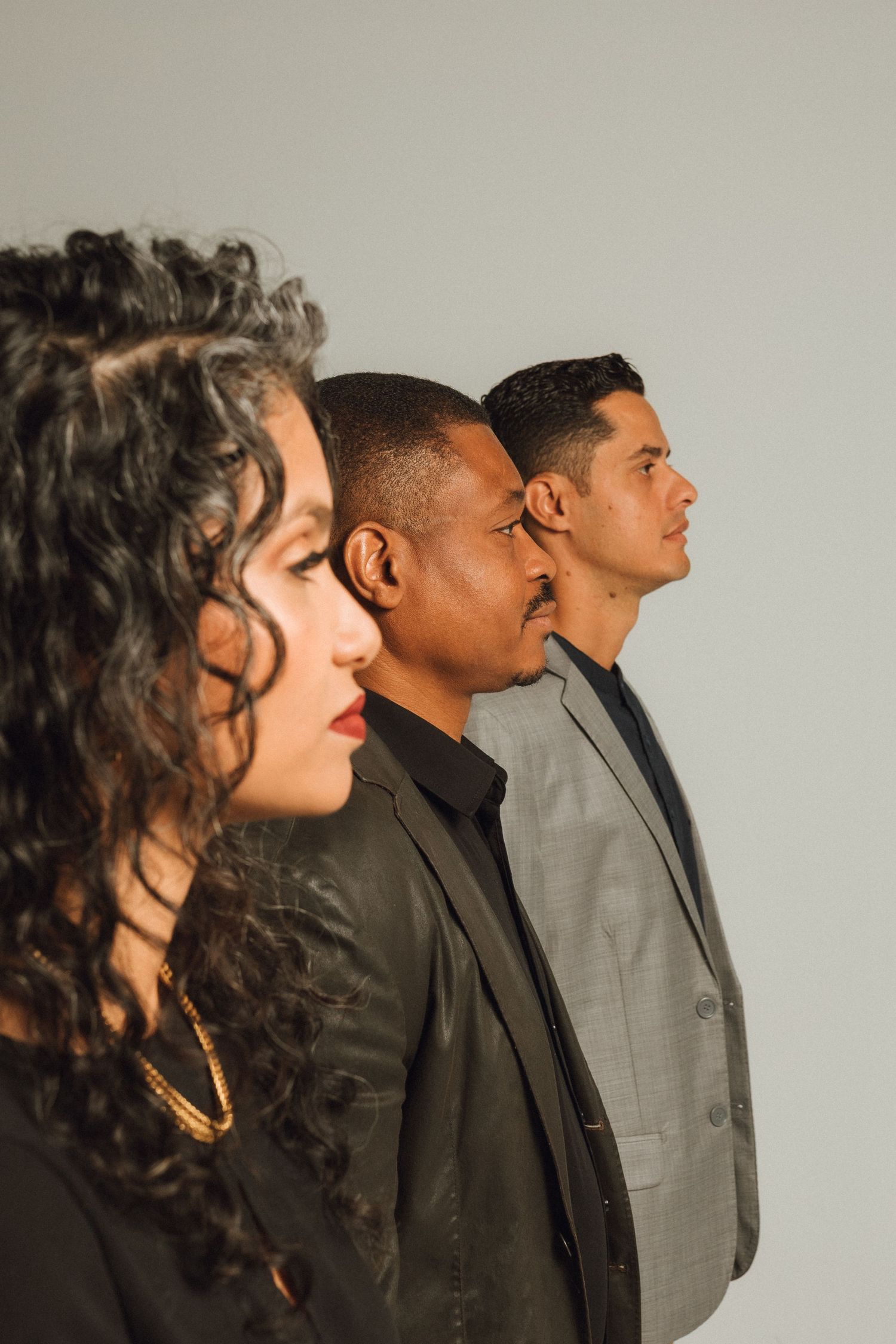 Three diverse professionals in formal attire posing in profile view.