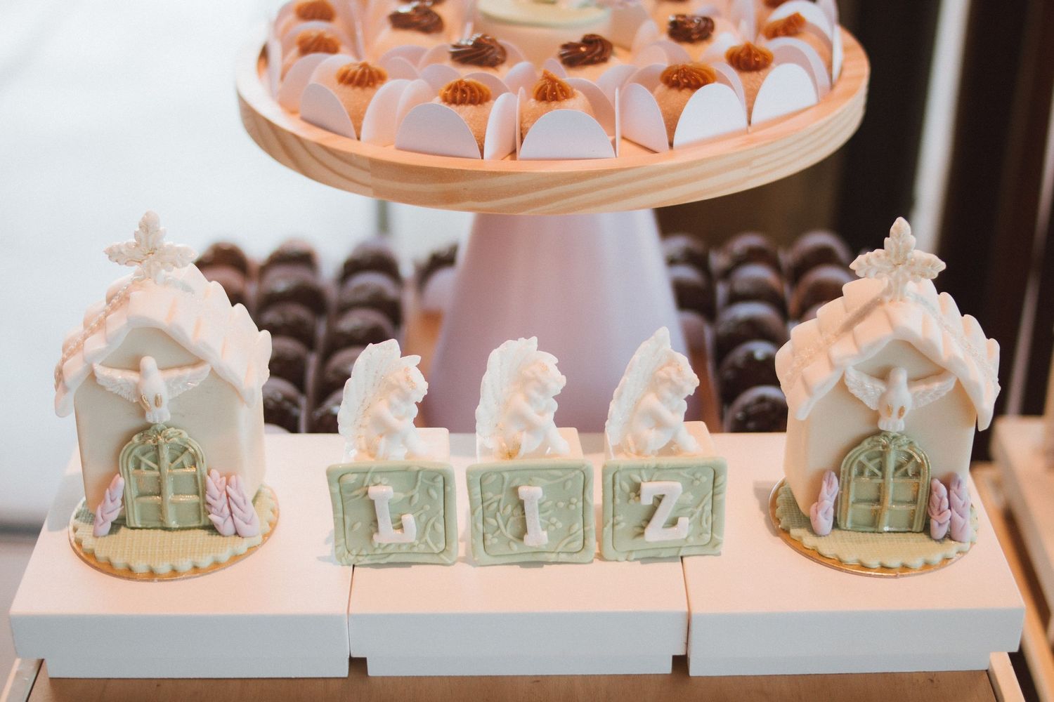 Elegant dessert table with sugar block letters spelling LIZ, gingerbread houses, seahorses, chocolates, and pink pastries.