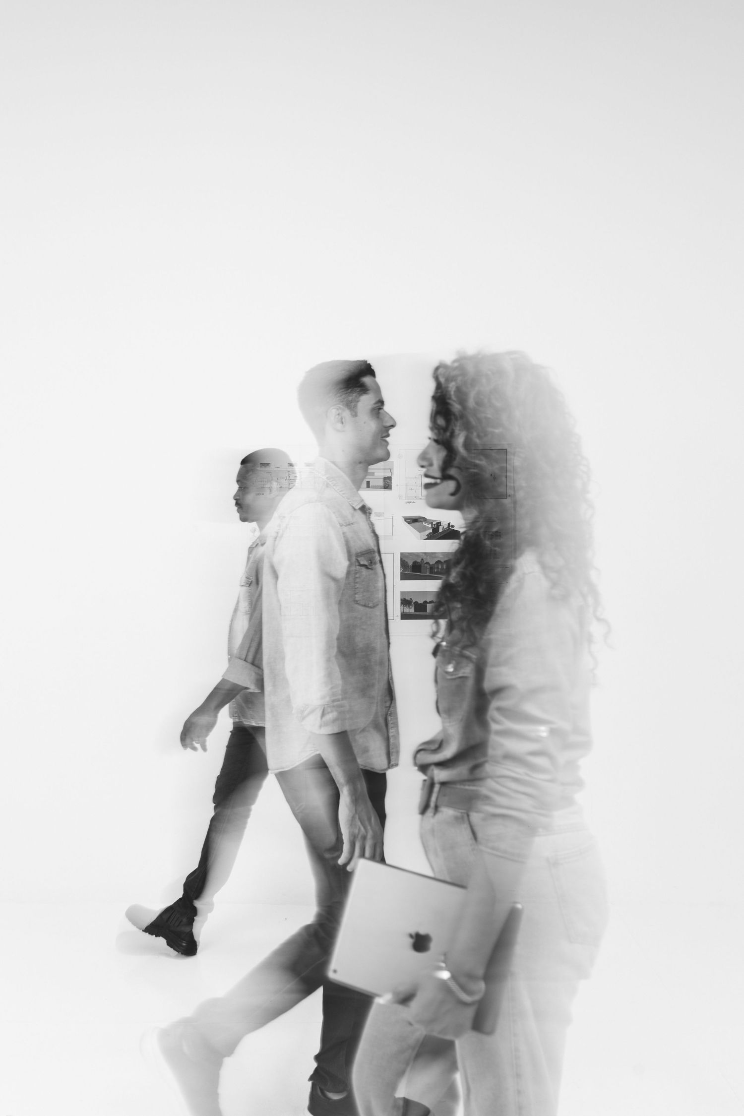 Black and white double exposure photo of diverse business professionals walking with laptop.