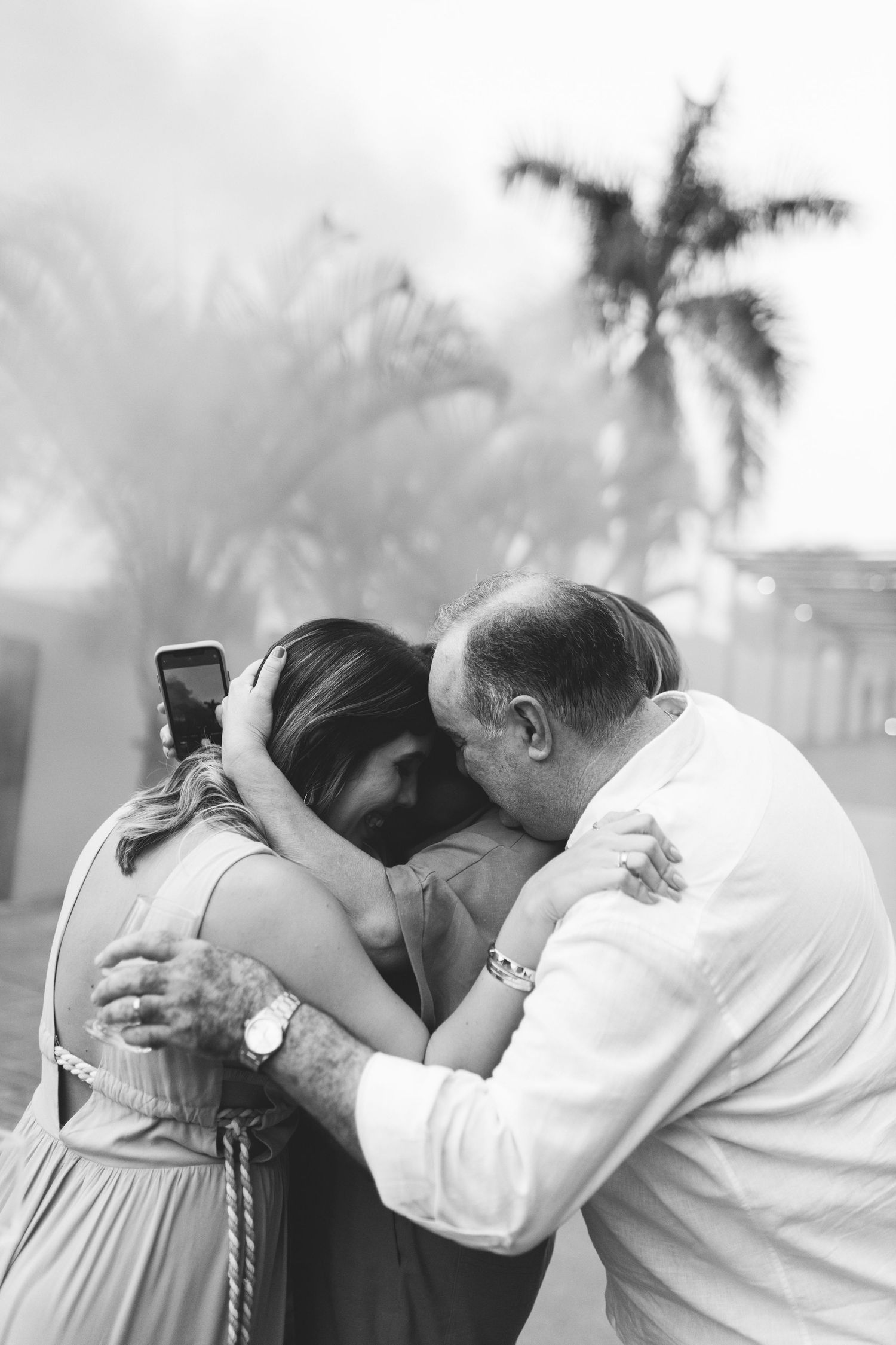 Emotional black and white photo of family embracing after gender reveal party outdoors.