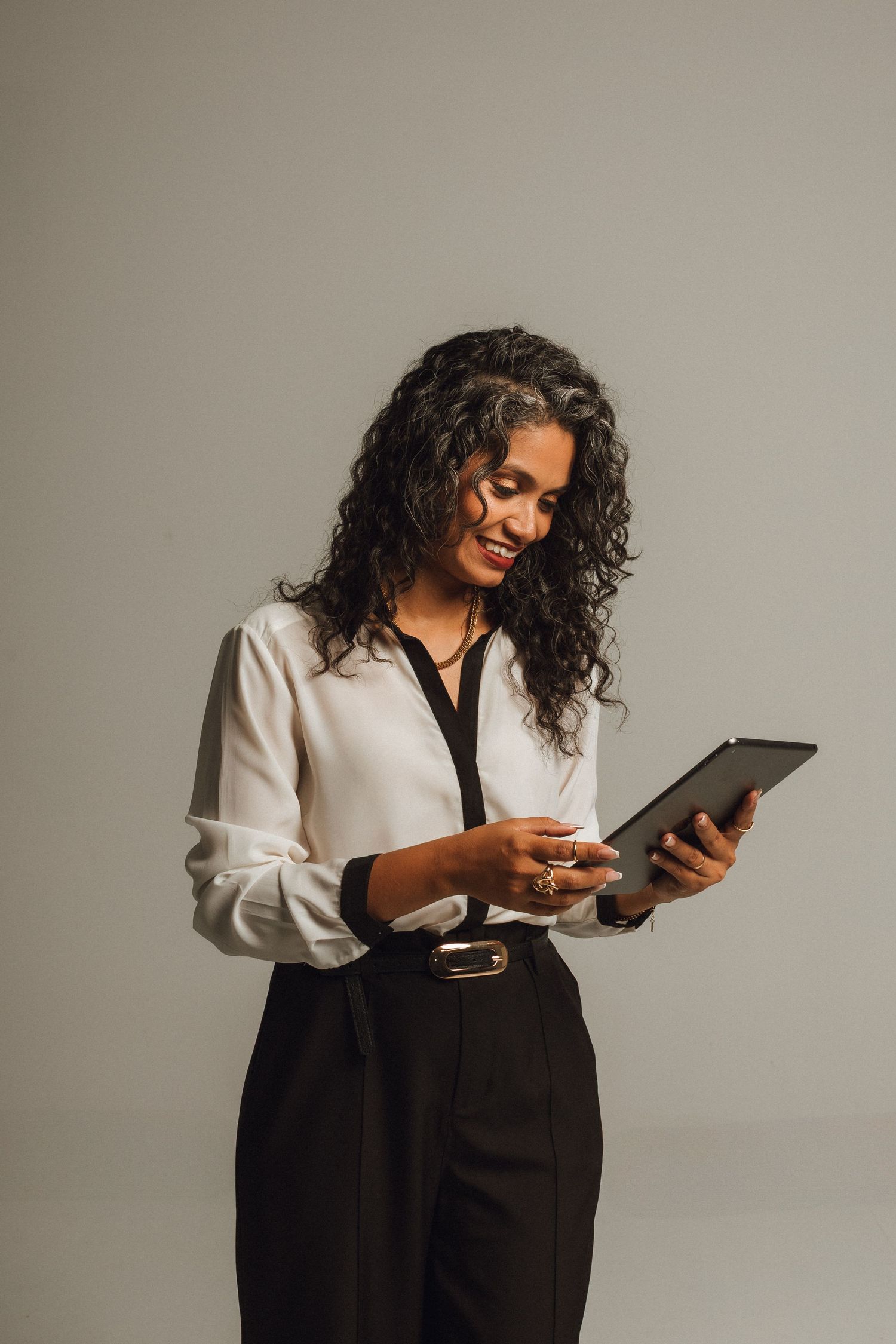 Professional woman with curly hair using digital tablet in studio.