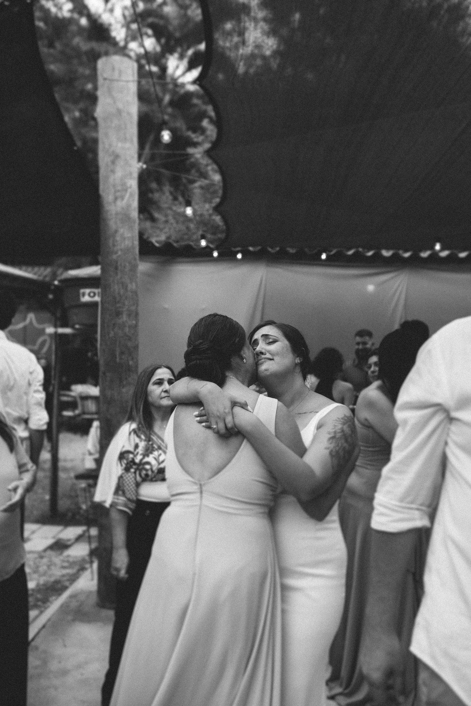 Two brides share an intimate dance embrace at their wedding reception outdoor celebration.