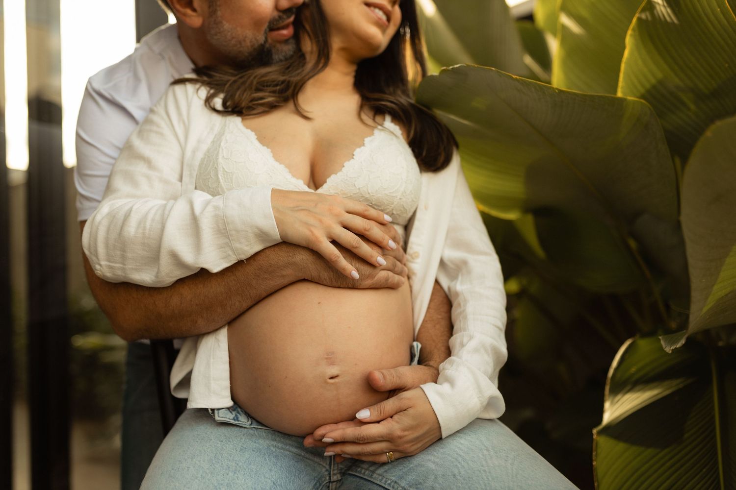 Couple tenderly embracing during maternity photoshoot, man kissing pregnant woman's head while holding her baby bump.