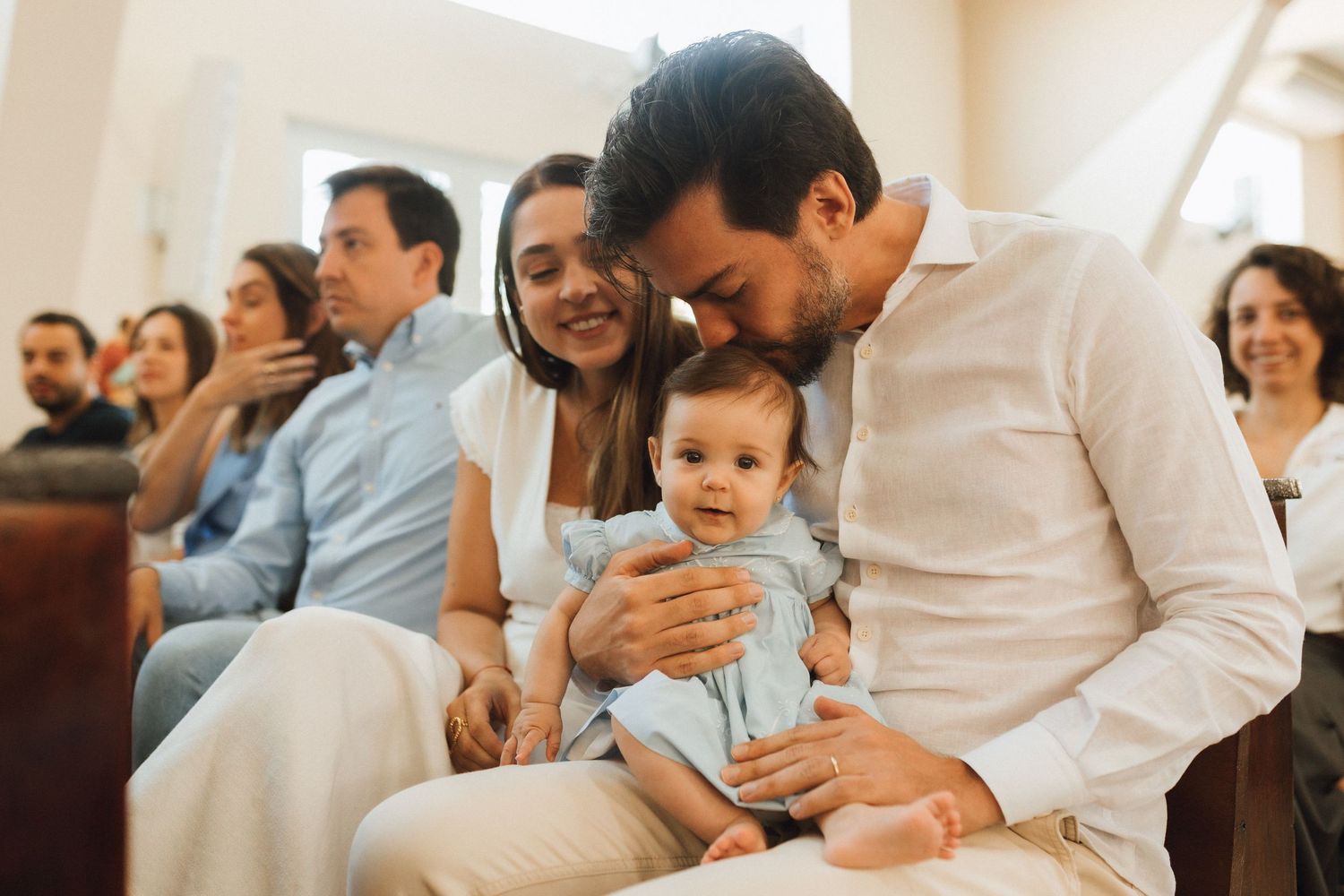 Happy family with baby at a christening ceremony, parents smiling at infant in a church setting.
