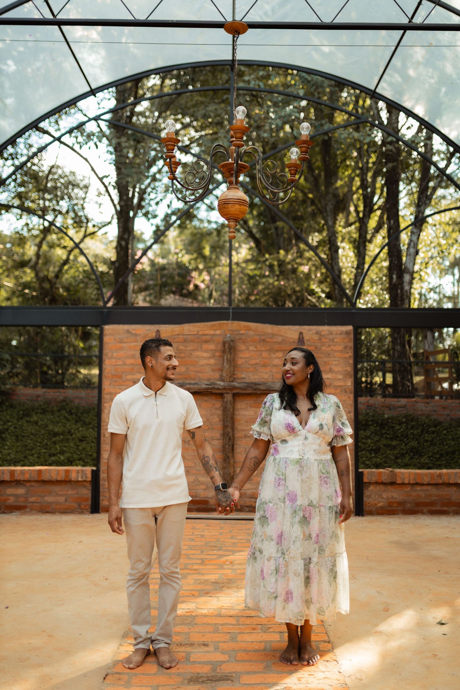 Happy couple holding hands standing under ornate arch with cross backdrop.